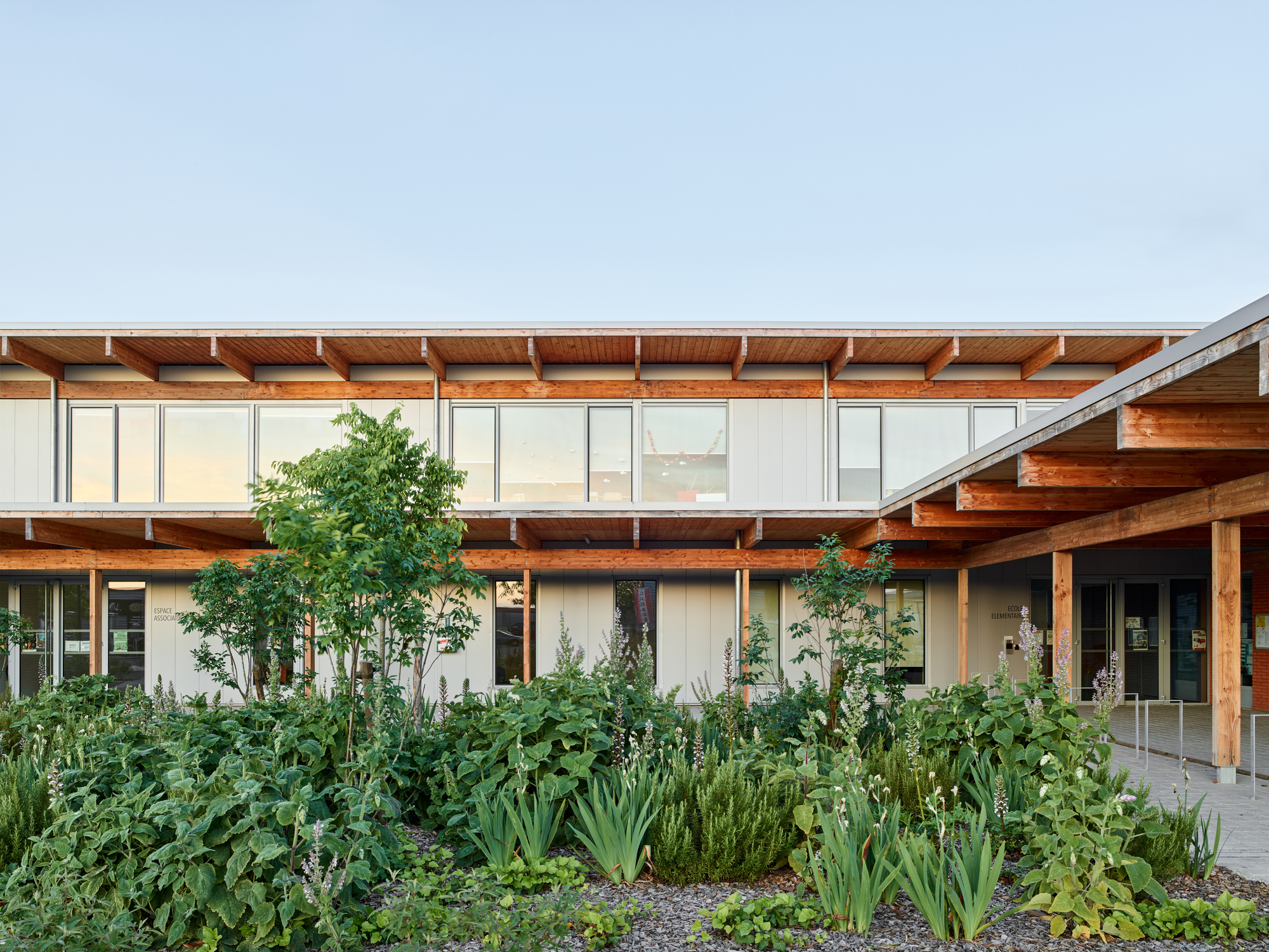 Central courtyard garden with dense plantings framed by timber beams and white-paneled facade wings