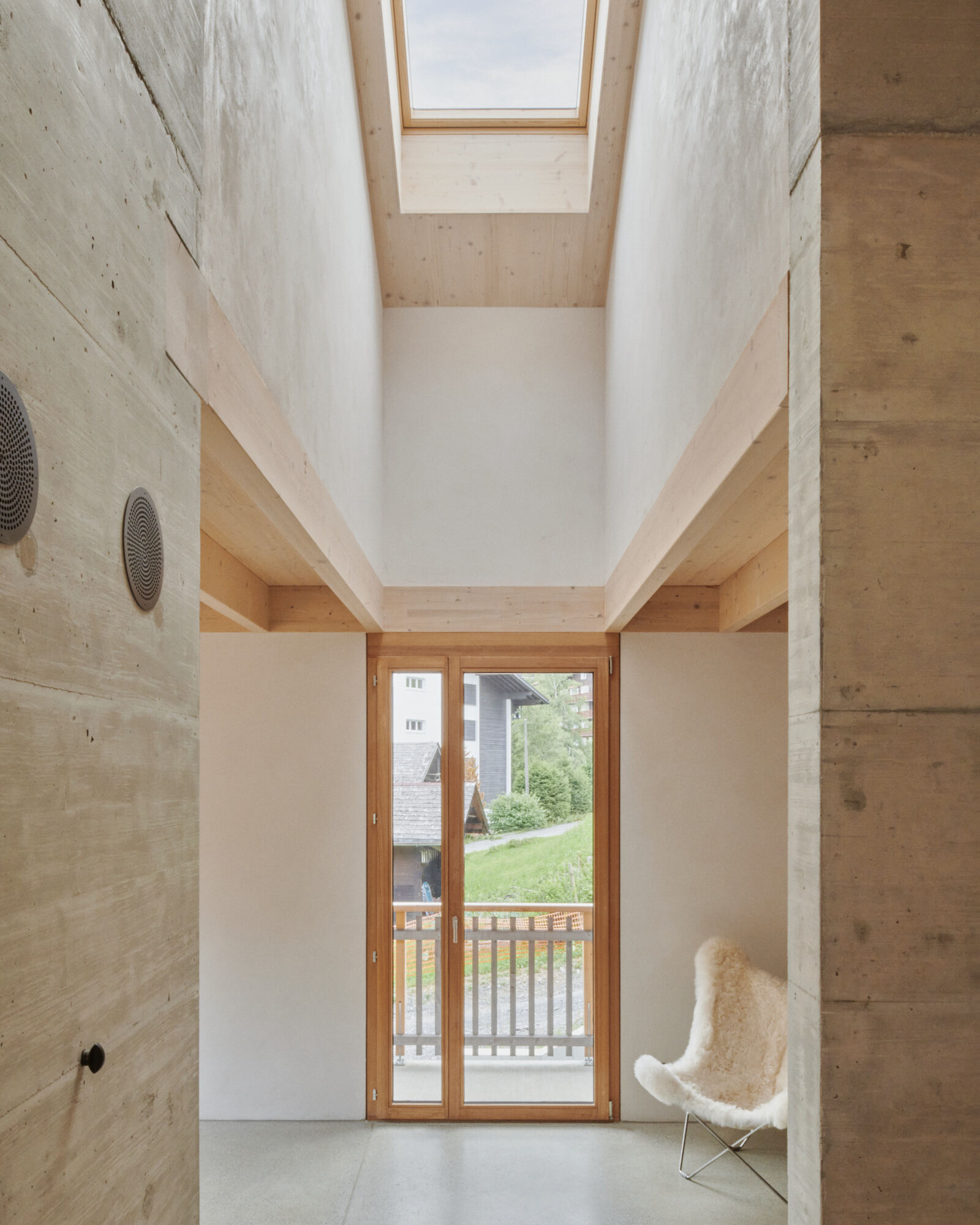 Double-height space with skylight above timber balcony and glazed doors opening to garden
