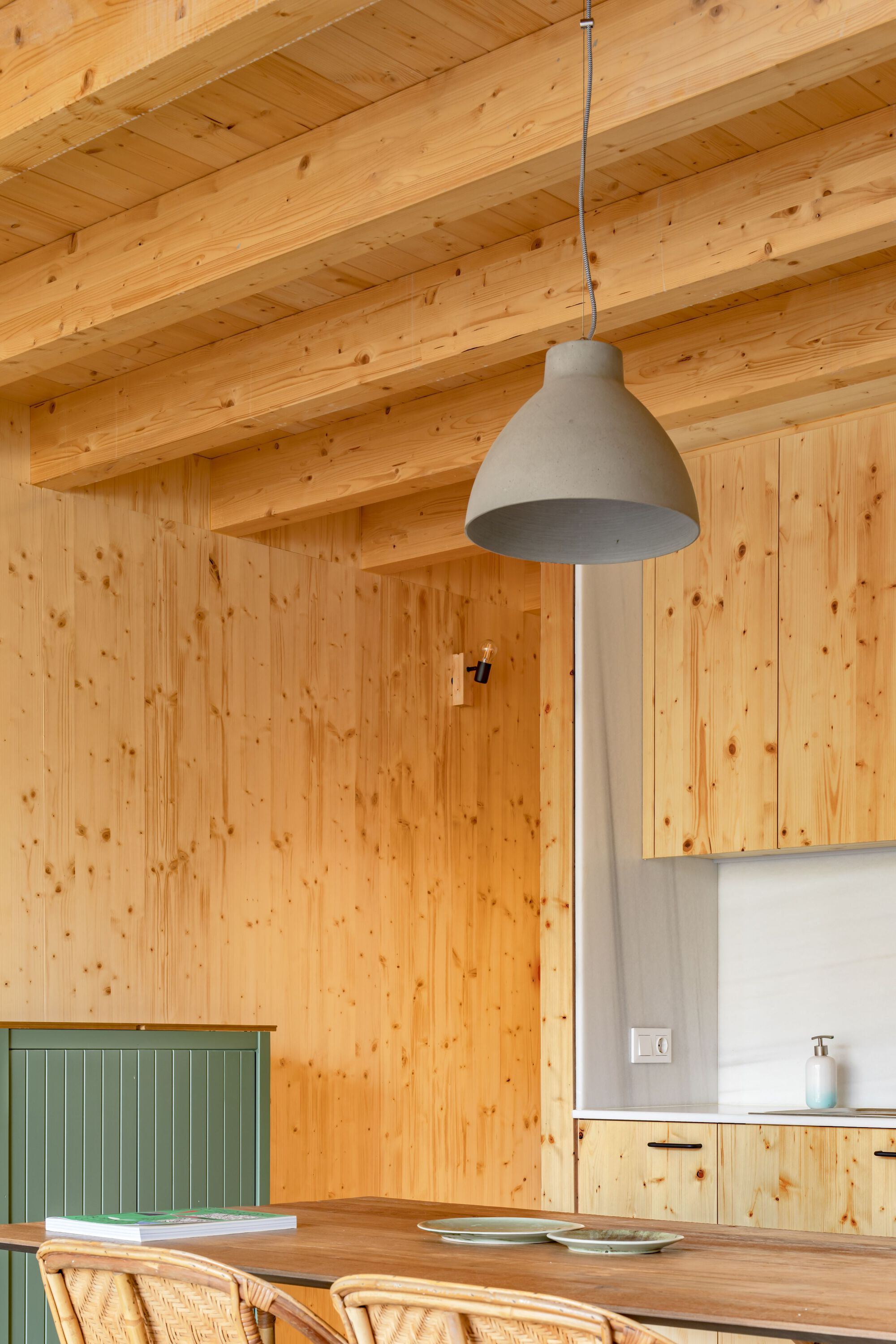 Kitchen interior with exposed timber beams and pendant light over a wooden dining table