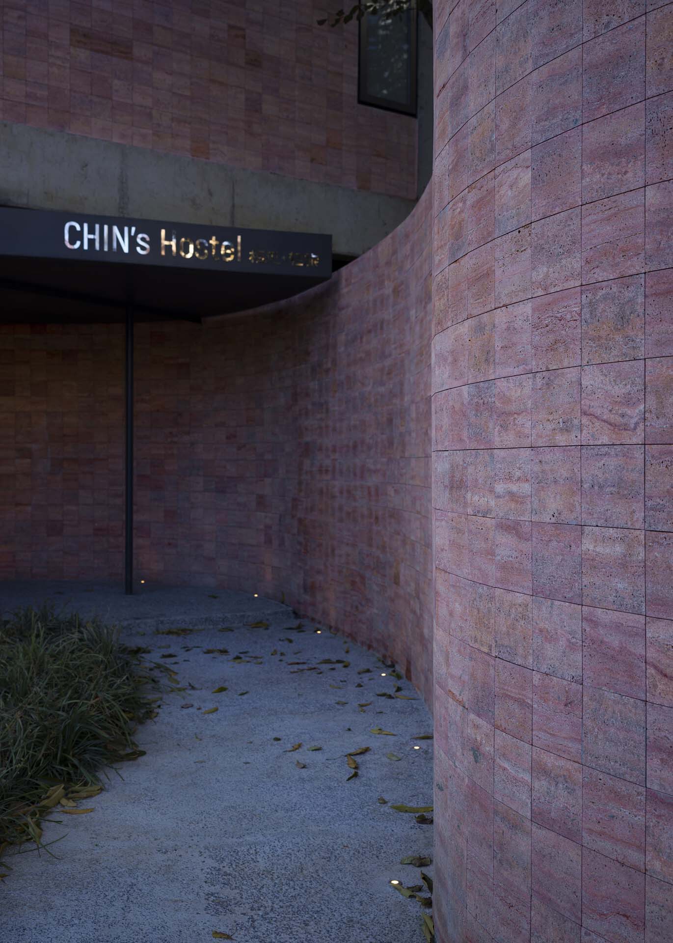 Curved entrance passage with red sandstone walls and scattered leaves on the pavement at dusk