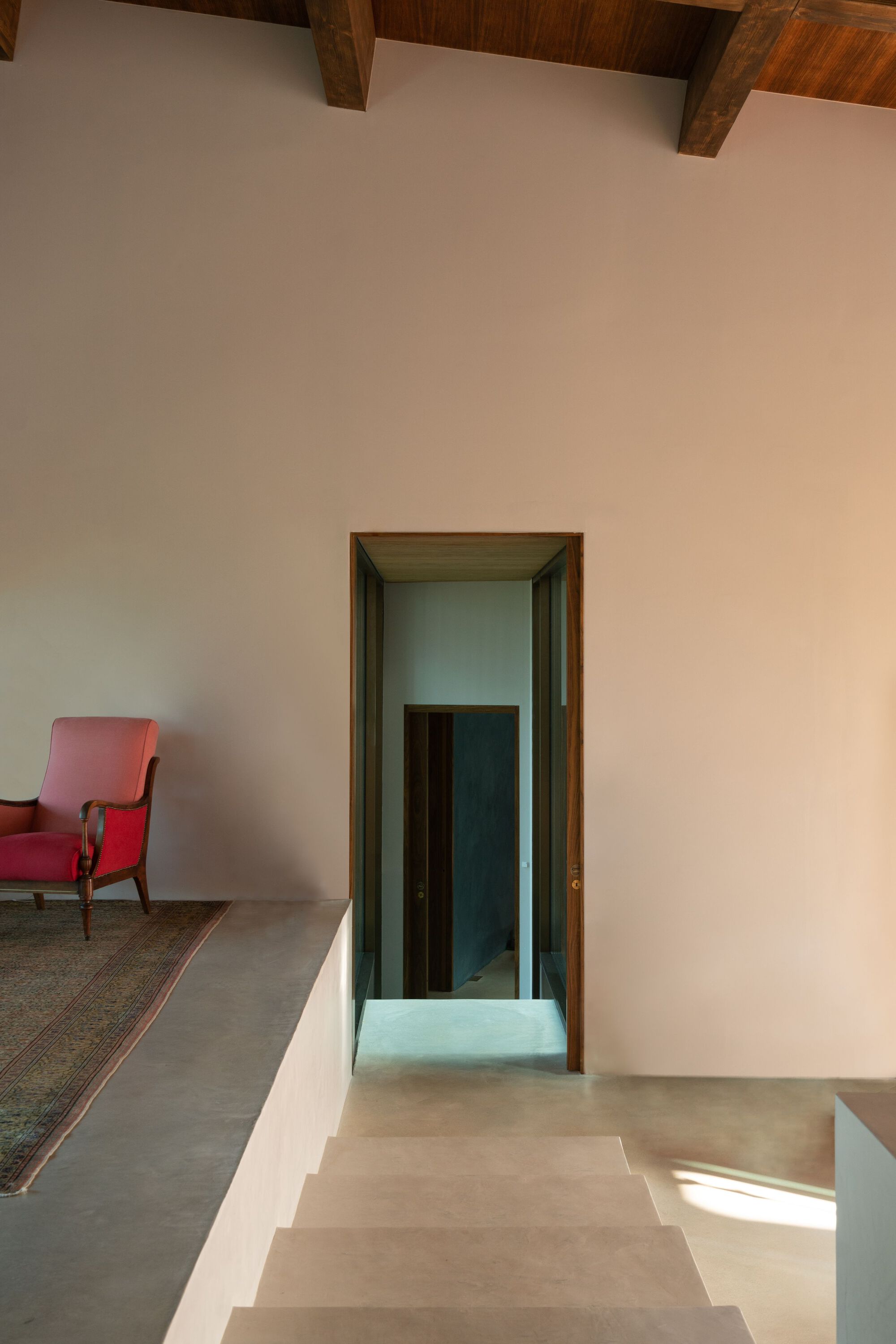 Interior doorway with timber frame and sunken threshold beneath an exposed beam ceiling