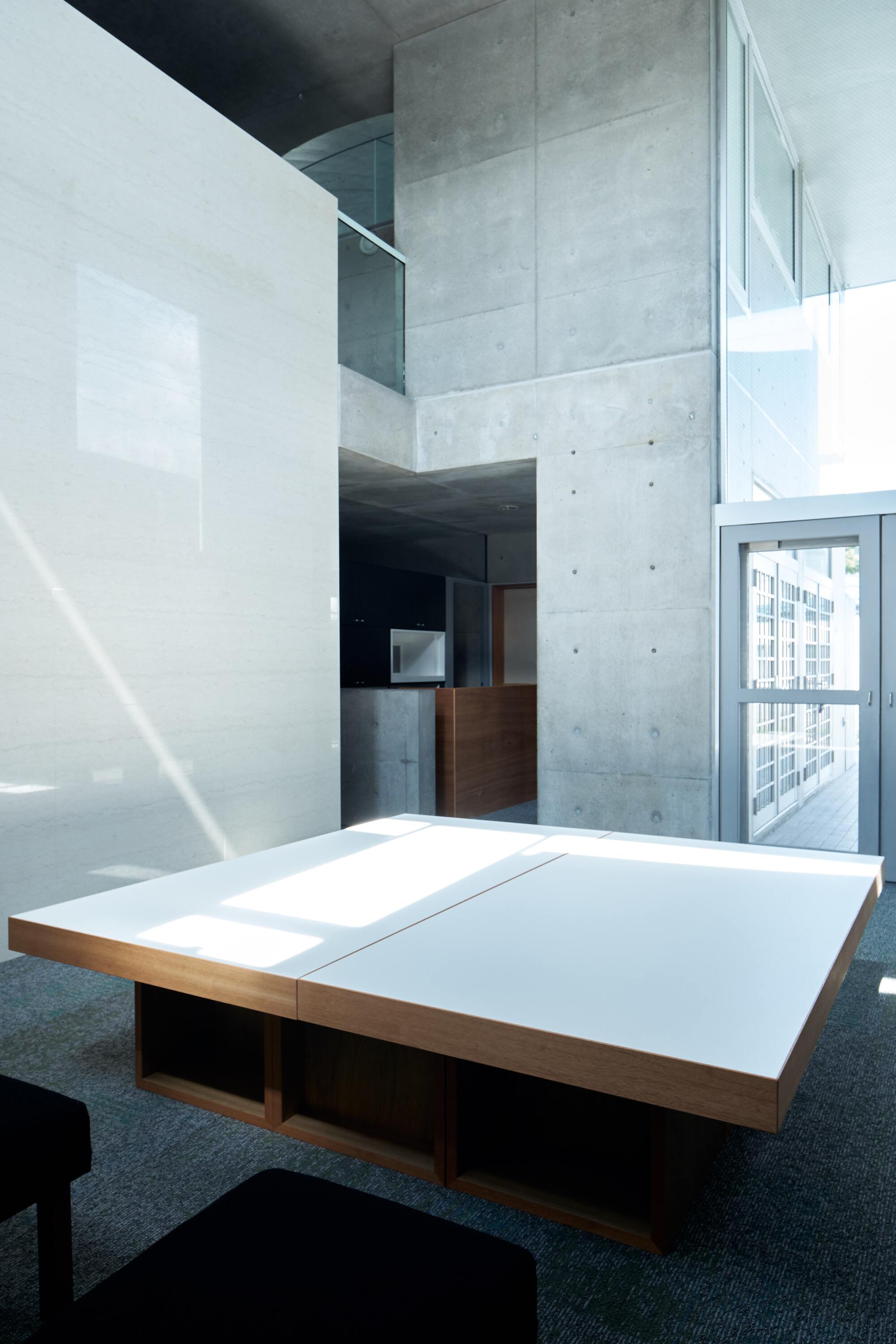 Corner view of the wooden table and mezzanine level with sunlight entering through high windows