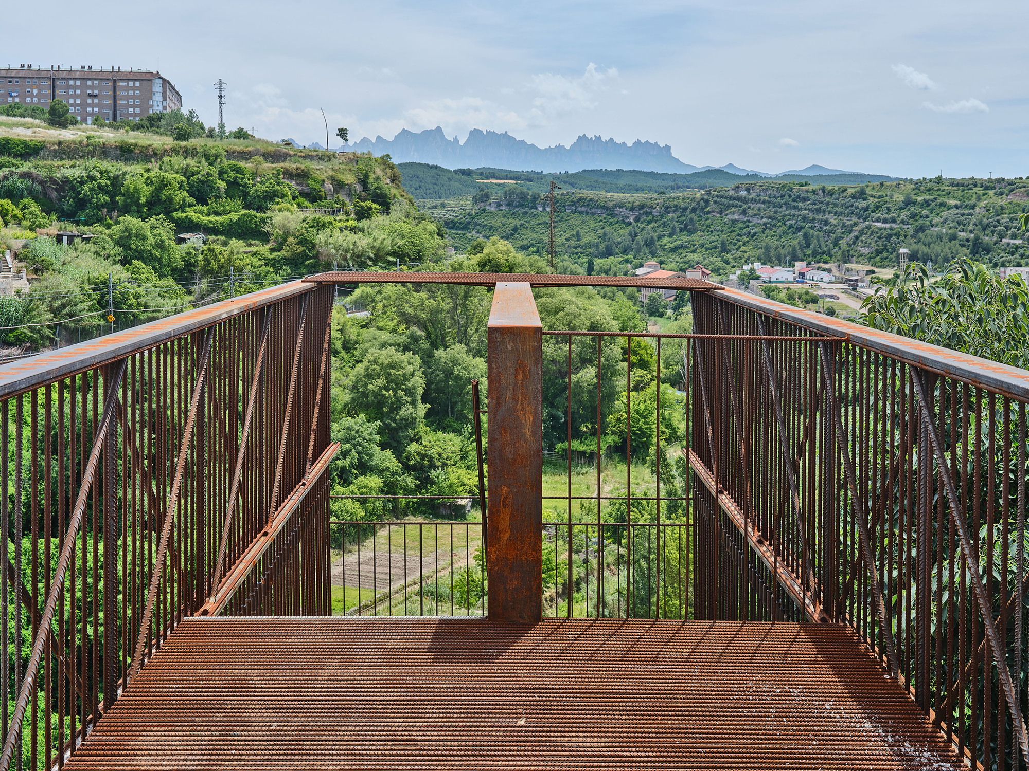 Upper platform deck framing a view of distant jagged mountains across a valley of trees