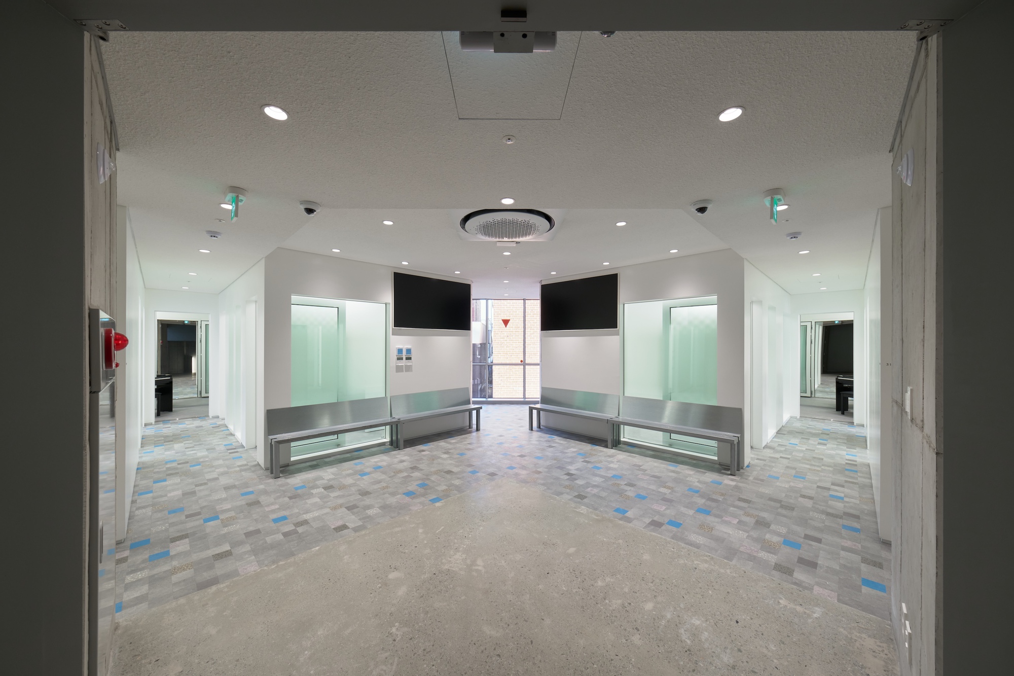 Interior lobby with patterned terrazzo floor, built-in benches and glazed openings at both ends