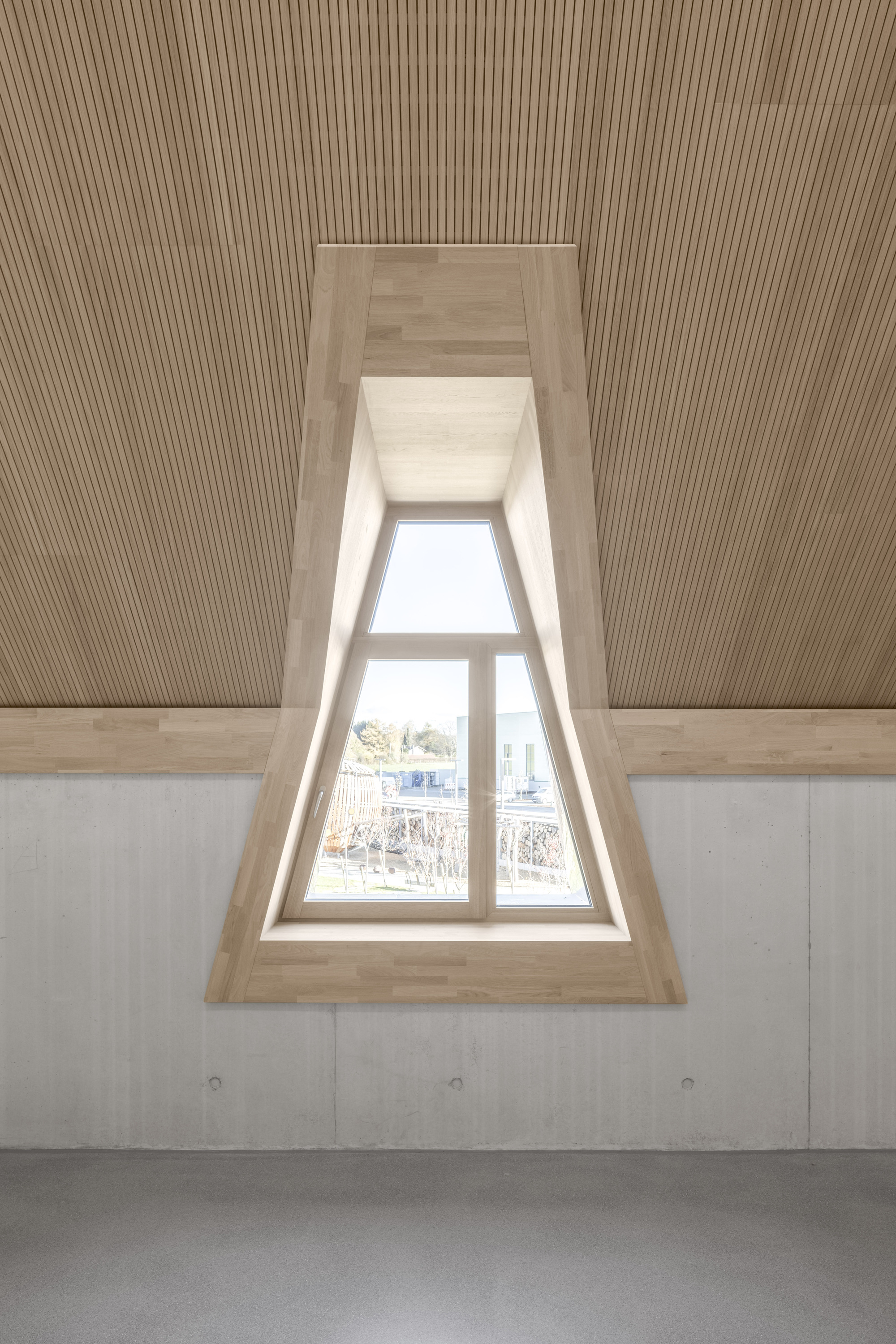 Recessed triangular dormer window with timber lining and ribbed ceiling above bare concrete walls