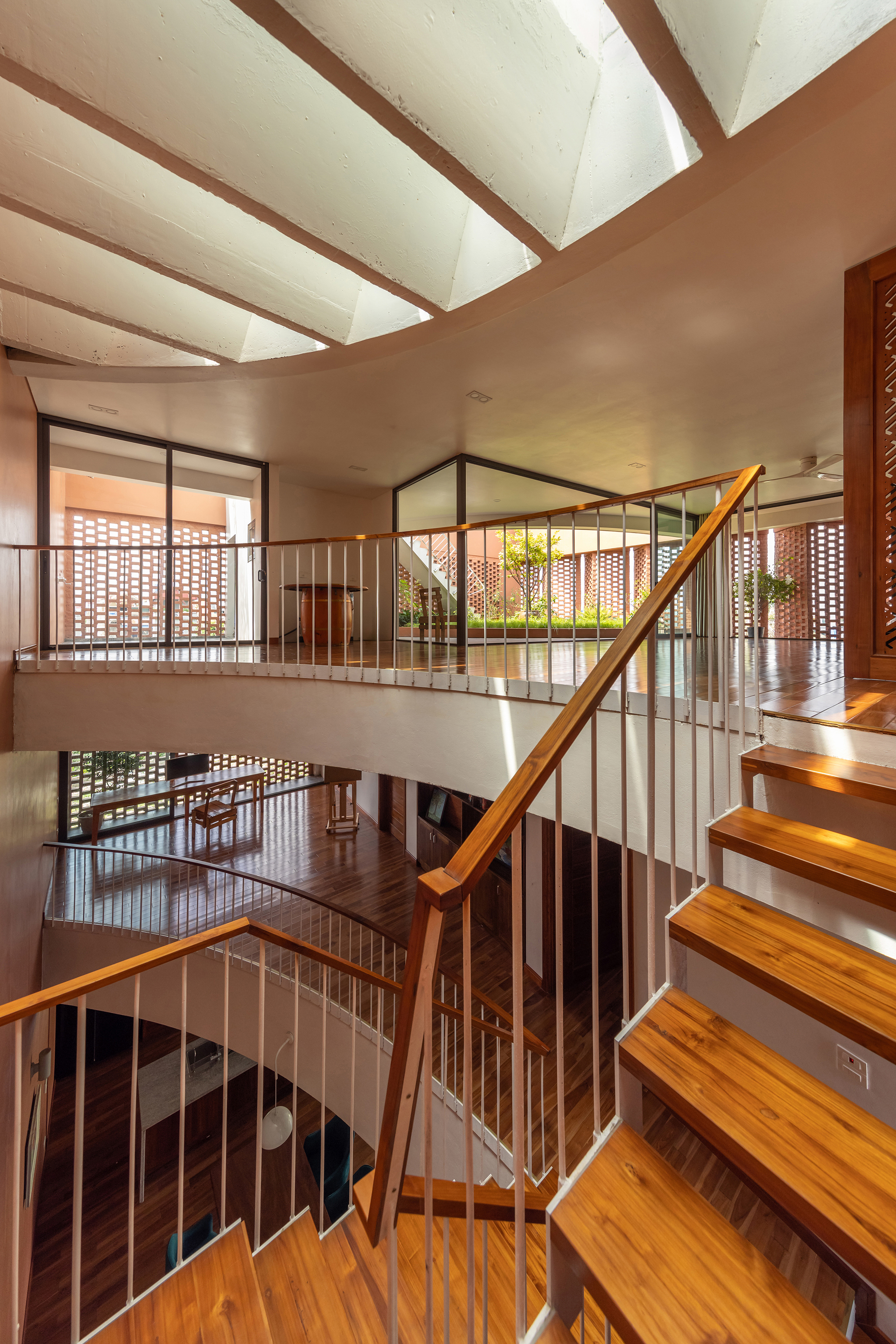 Multi-level staircase with timber treads and metal railings wrapping around an open courtyard void
