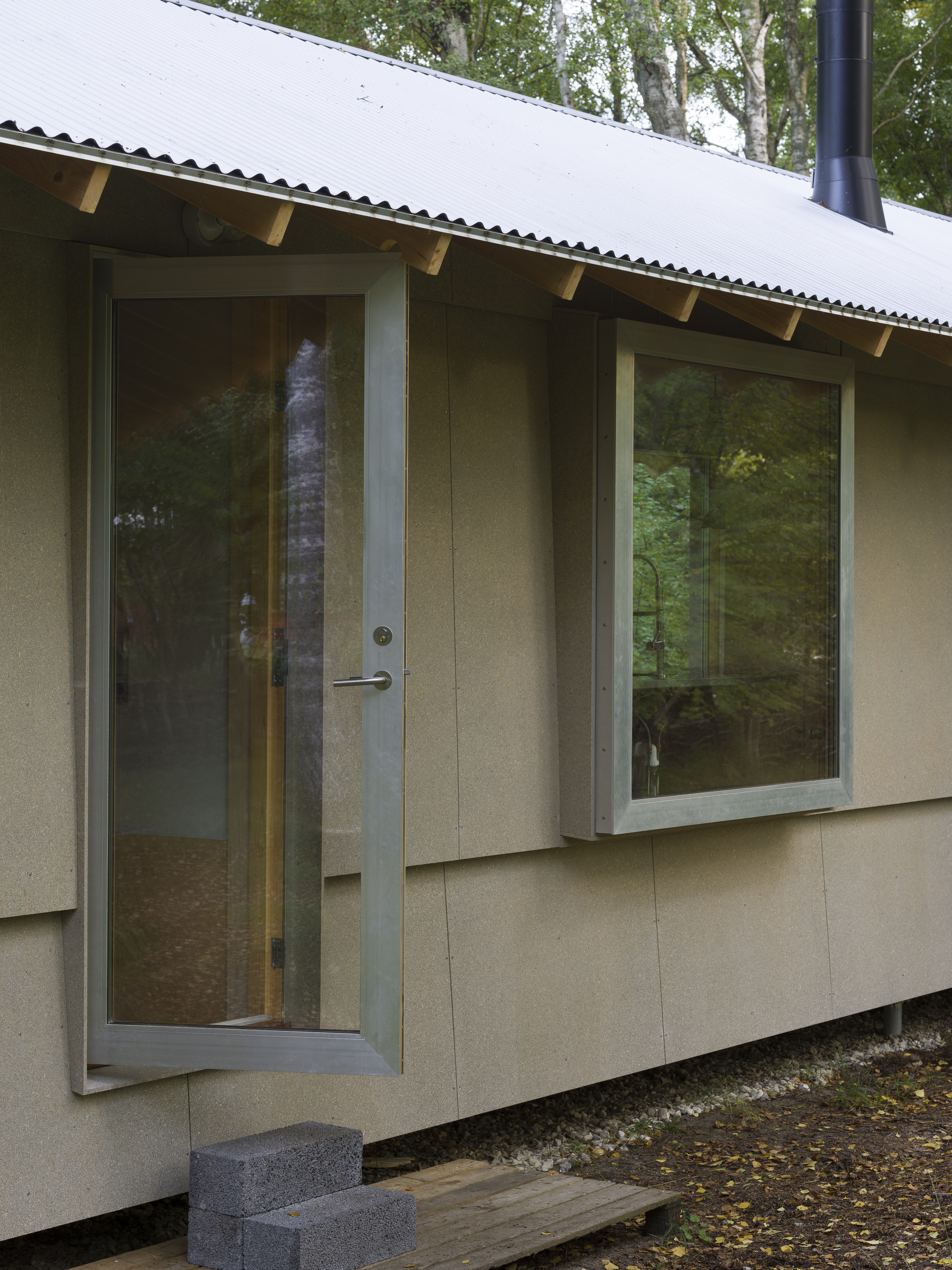Close-up of the entrance door and window corner with exposed timber rafter brackets overhead