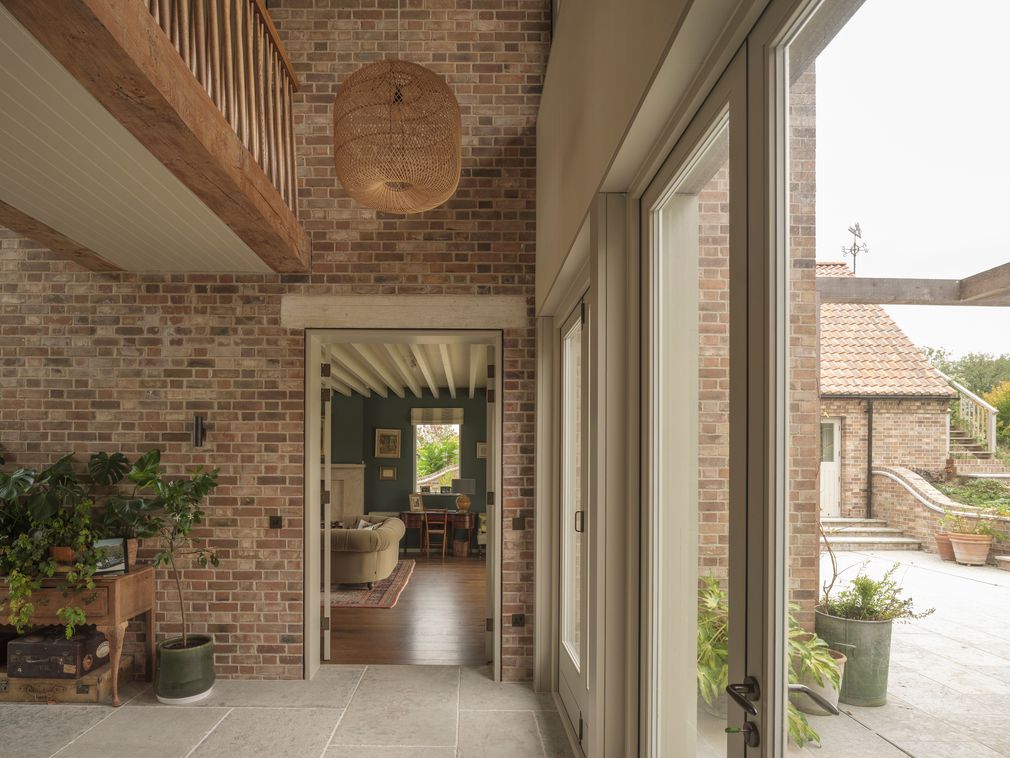 Glazed doorway opening from the tiled courtyard through exposed brick walls into the living space