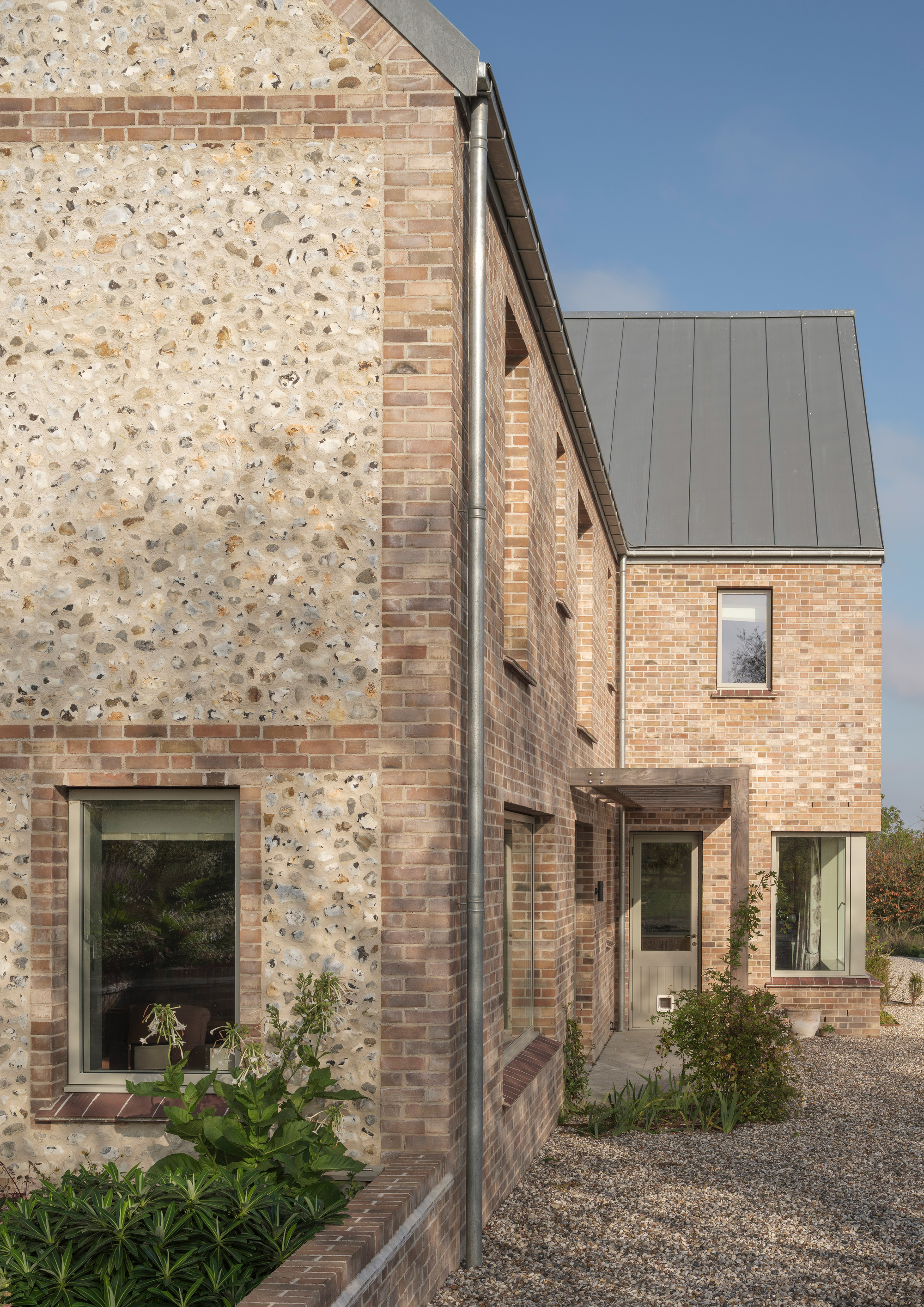 Cluster of brick volumes with standing seam metal roof under a clear blue sky