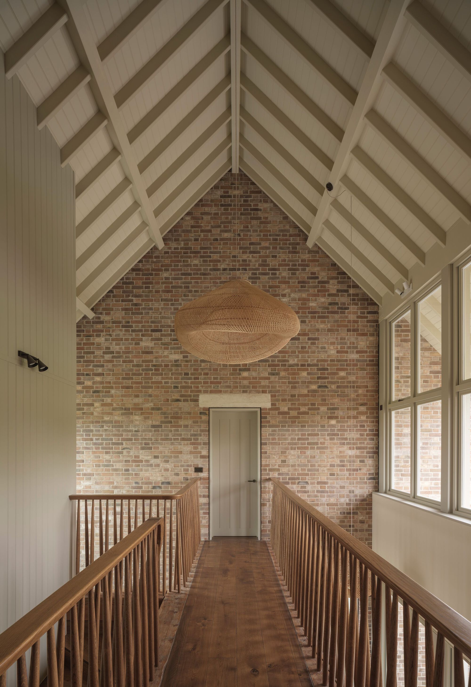 Upper landing with vaulted timber ceiling and brick gable wall flanked by wooden balustrades