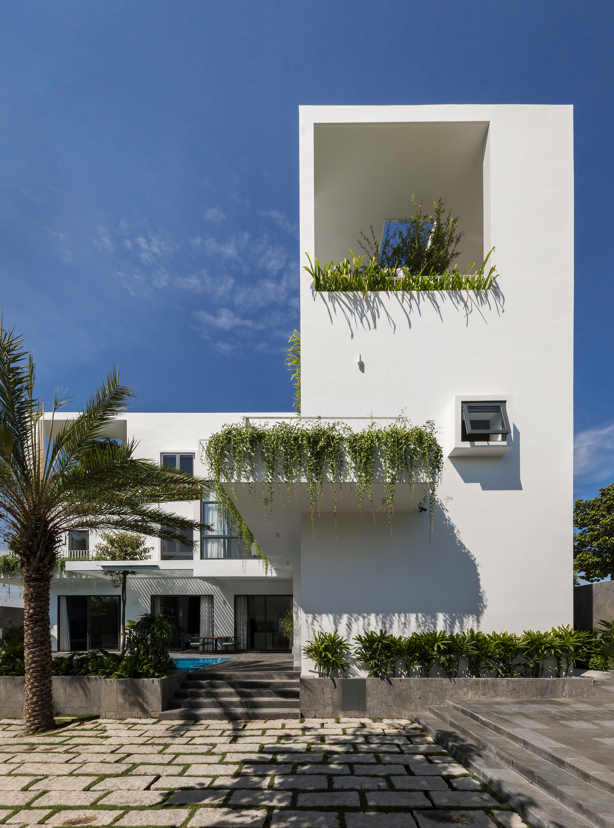 Rear garden elevation showing stepped terraces with trailing plants and paved courtyard below