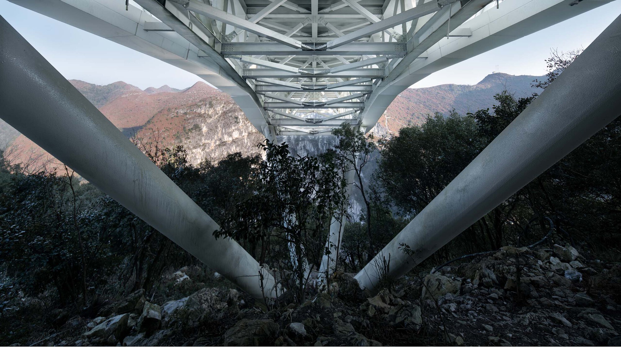 Underside view of the steel support columns and triangulated truss framework at dusk