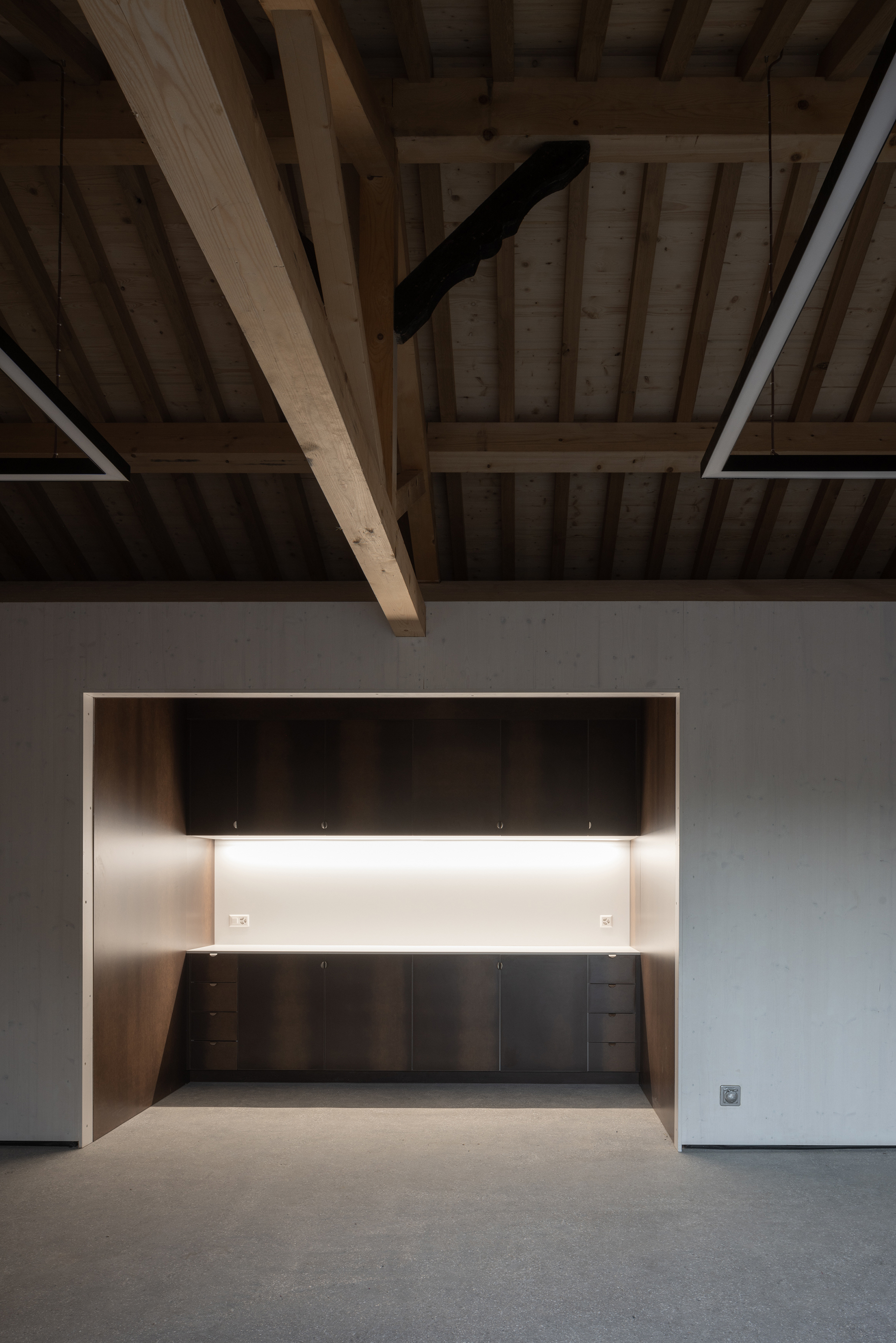 Interior alcove with illuminated counter beneath exposed timber beam ceiling and roof structure