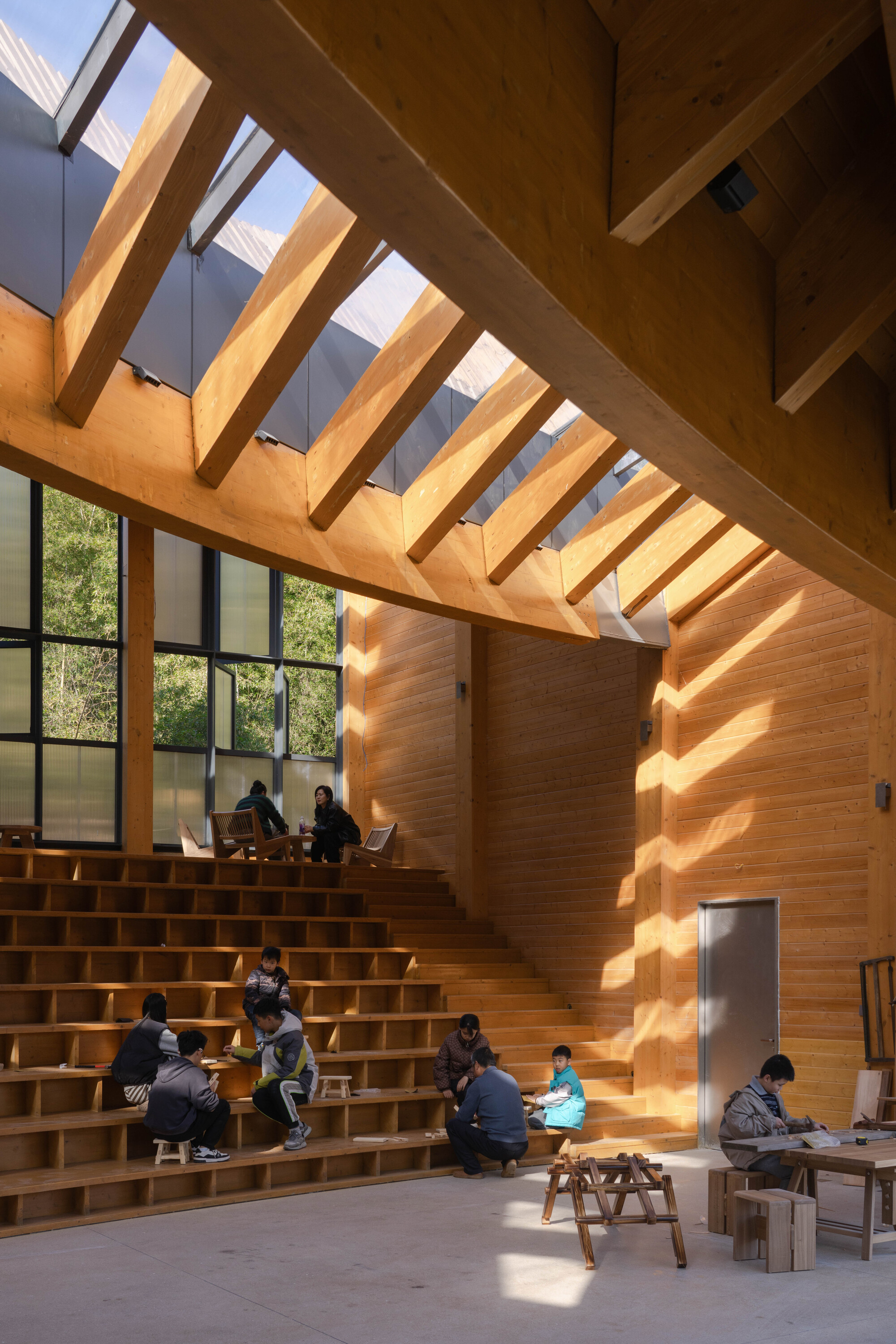 Tiered timber seating in use with children and adults under exposed rafters and skylights