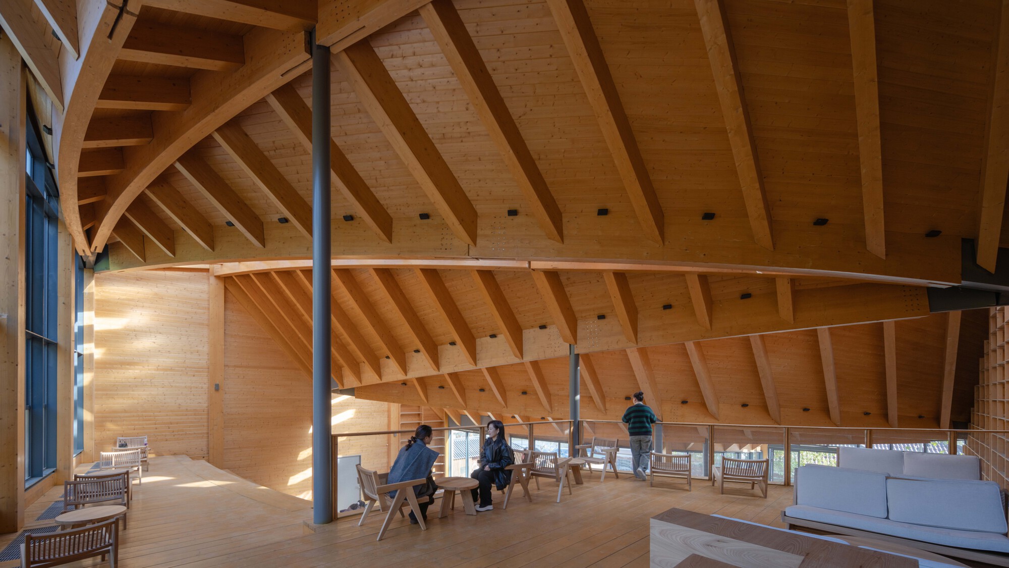 Interior view of the curved timber roof with exposed rafters and a central steel column supporting the structure