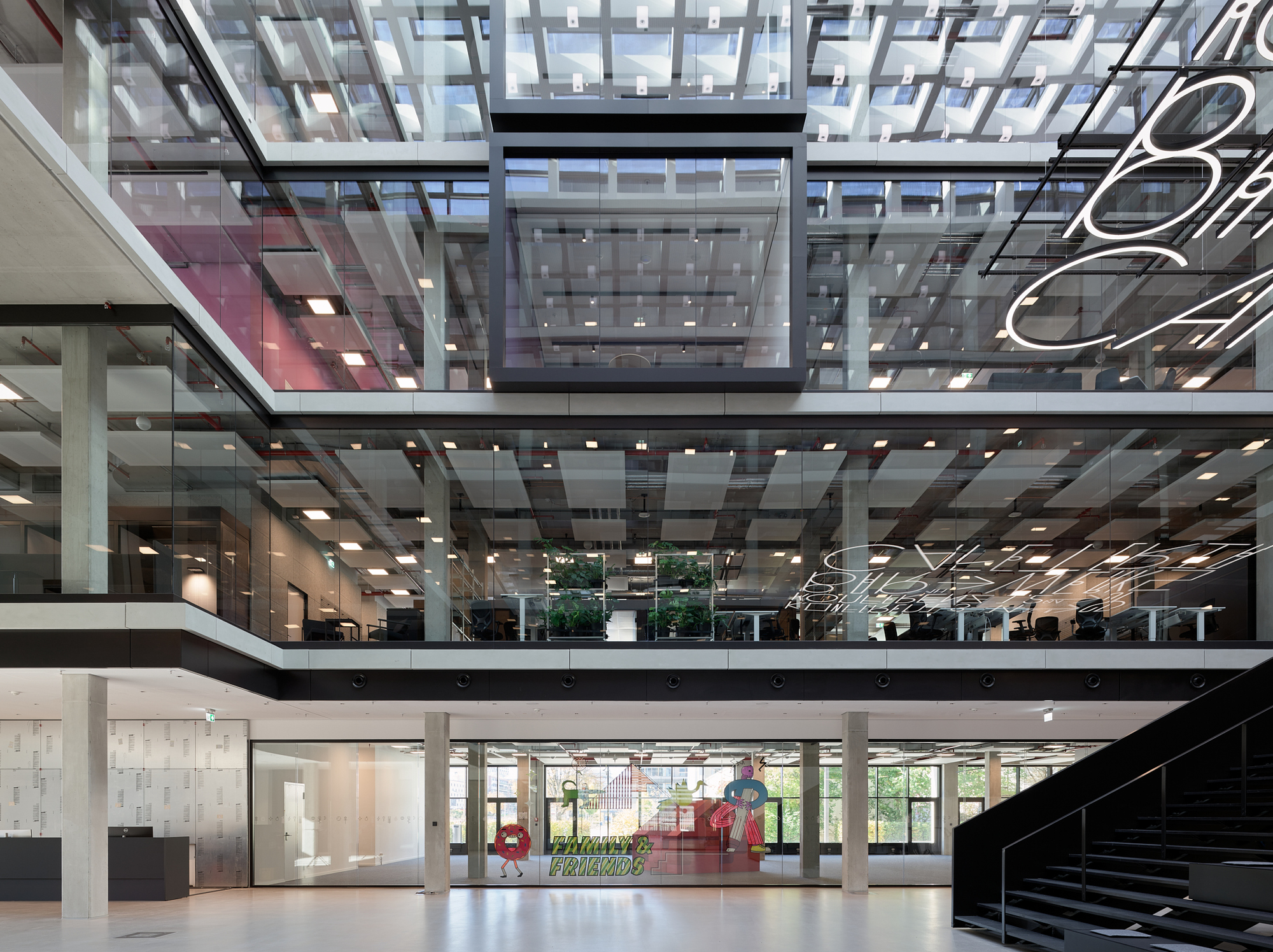 Glazed ceiling grid above stacked floor plates with planted greenery visible through the central opening