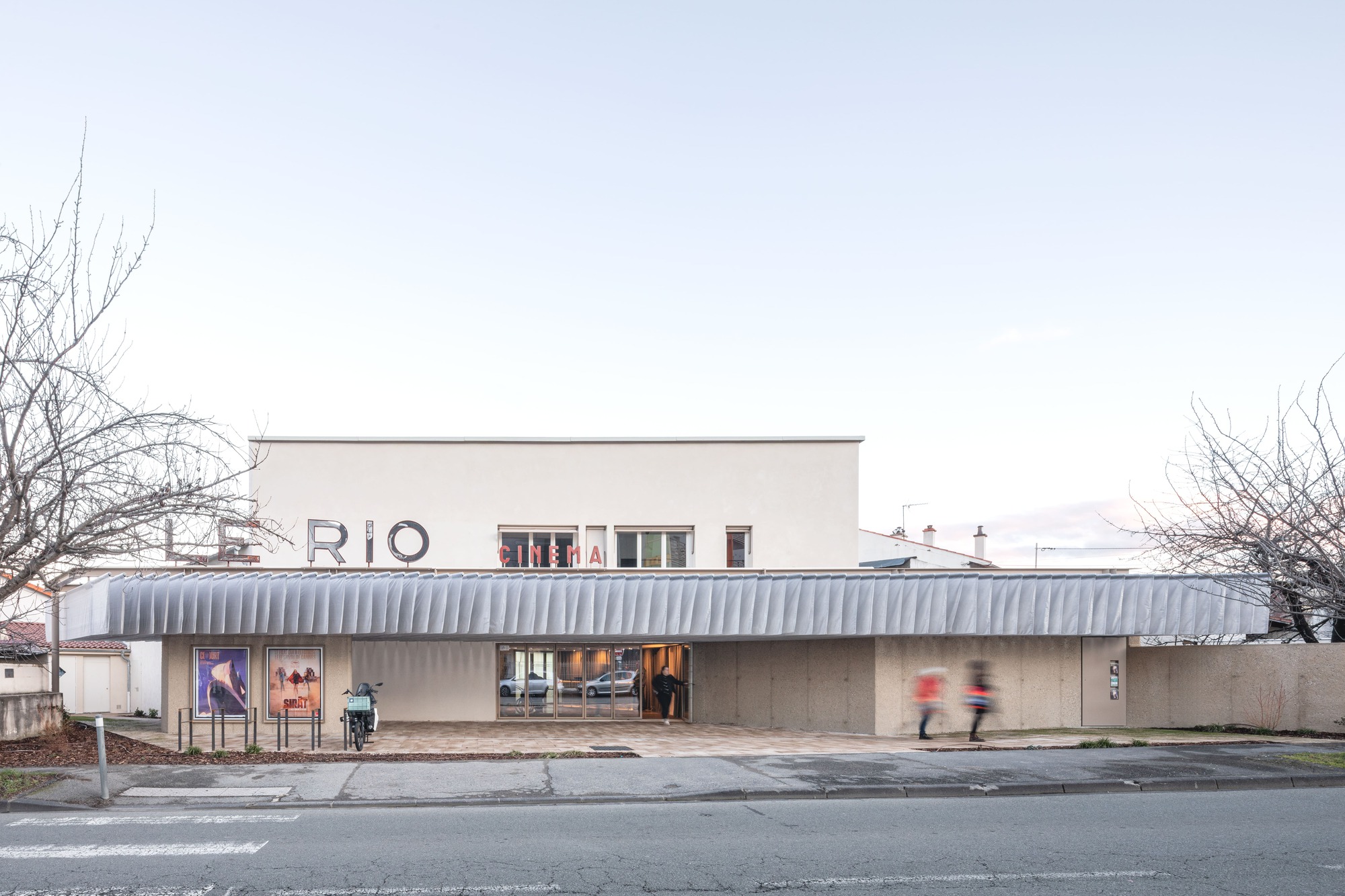 Street view of the cinema facade with corrugated metal canopy and bare winter trees