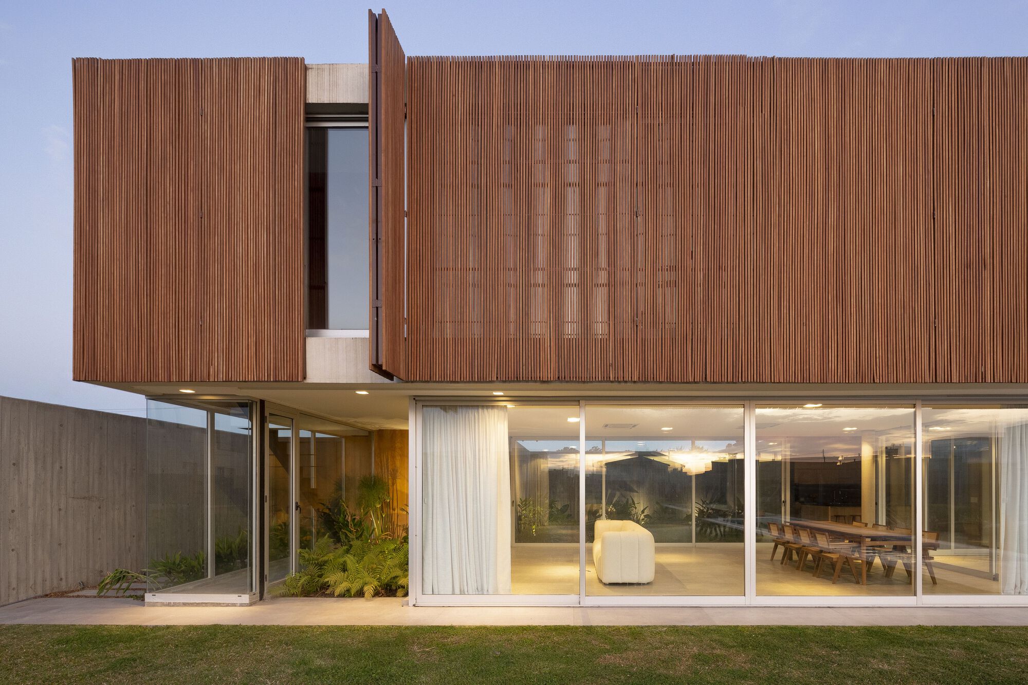 Upper-level timber screen with hinged window panel and illuminated interior at dusk