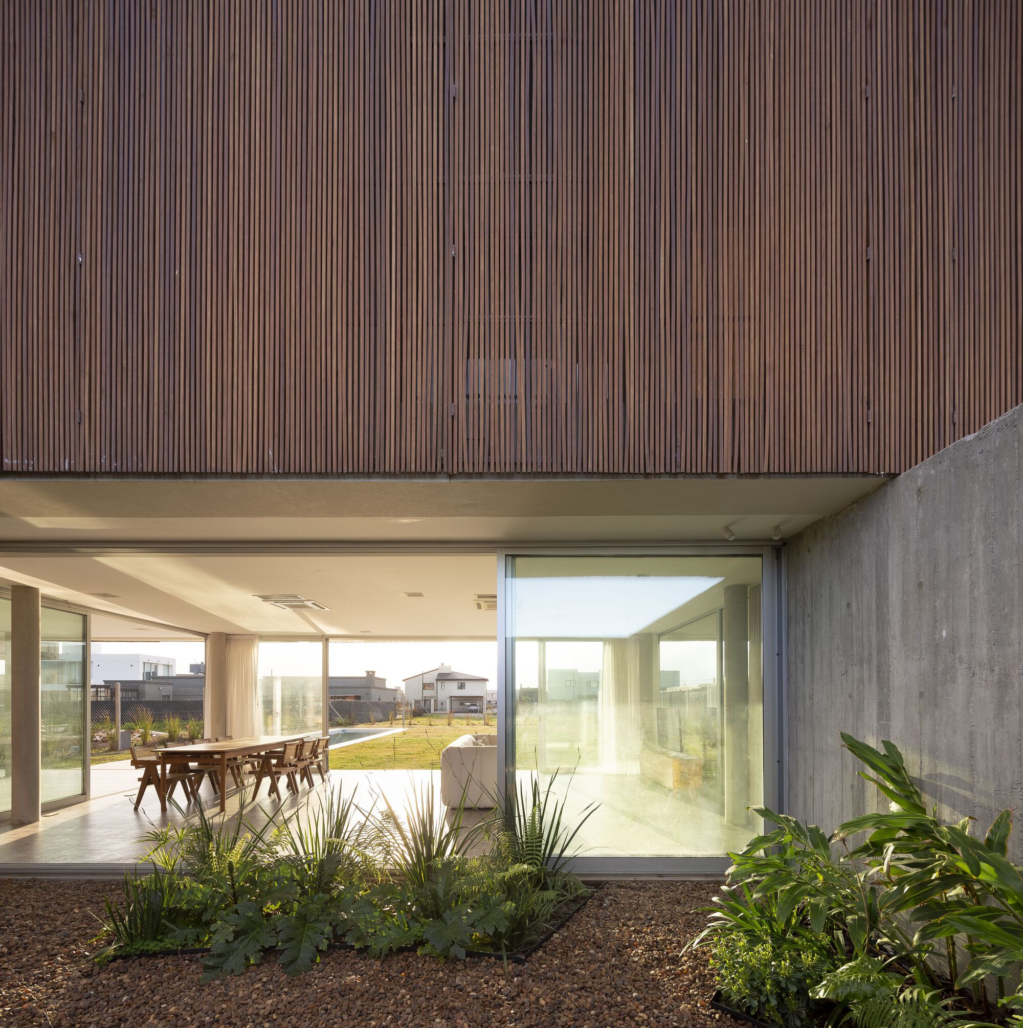 Internal courtyard with planted beds beneath timber-clad overhang and concrete boundary wall