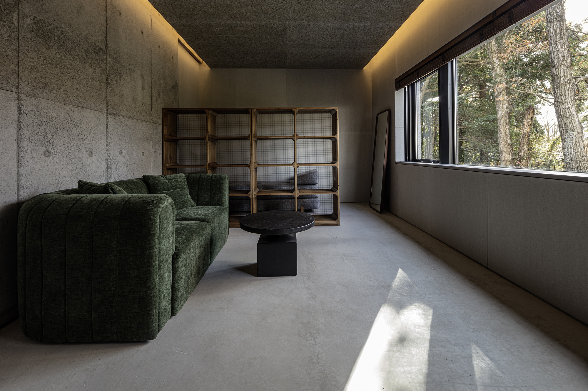 Interior room with concrete walls, cove lighting, and a gridded wood screen beside a window