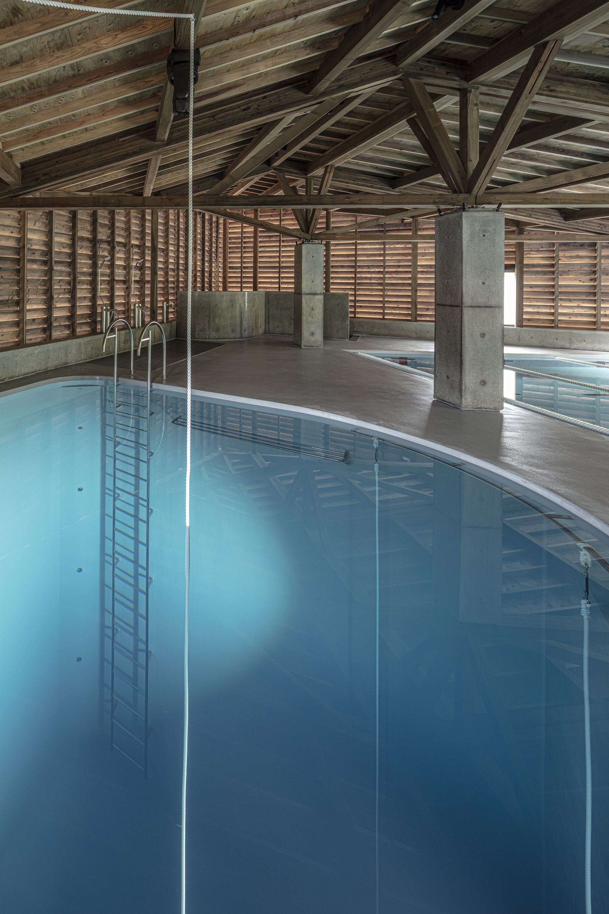 Corner of the pool showing ladder rails and horizontal slatted timber walls under timber beams