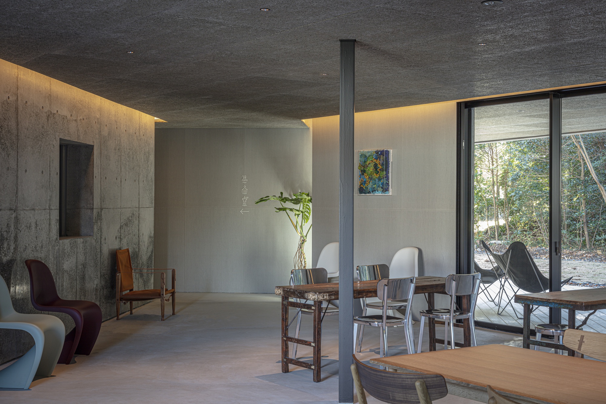 Living space with polished concrete floor, cove lighting, and glazed wall opening to the forest
