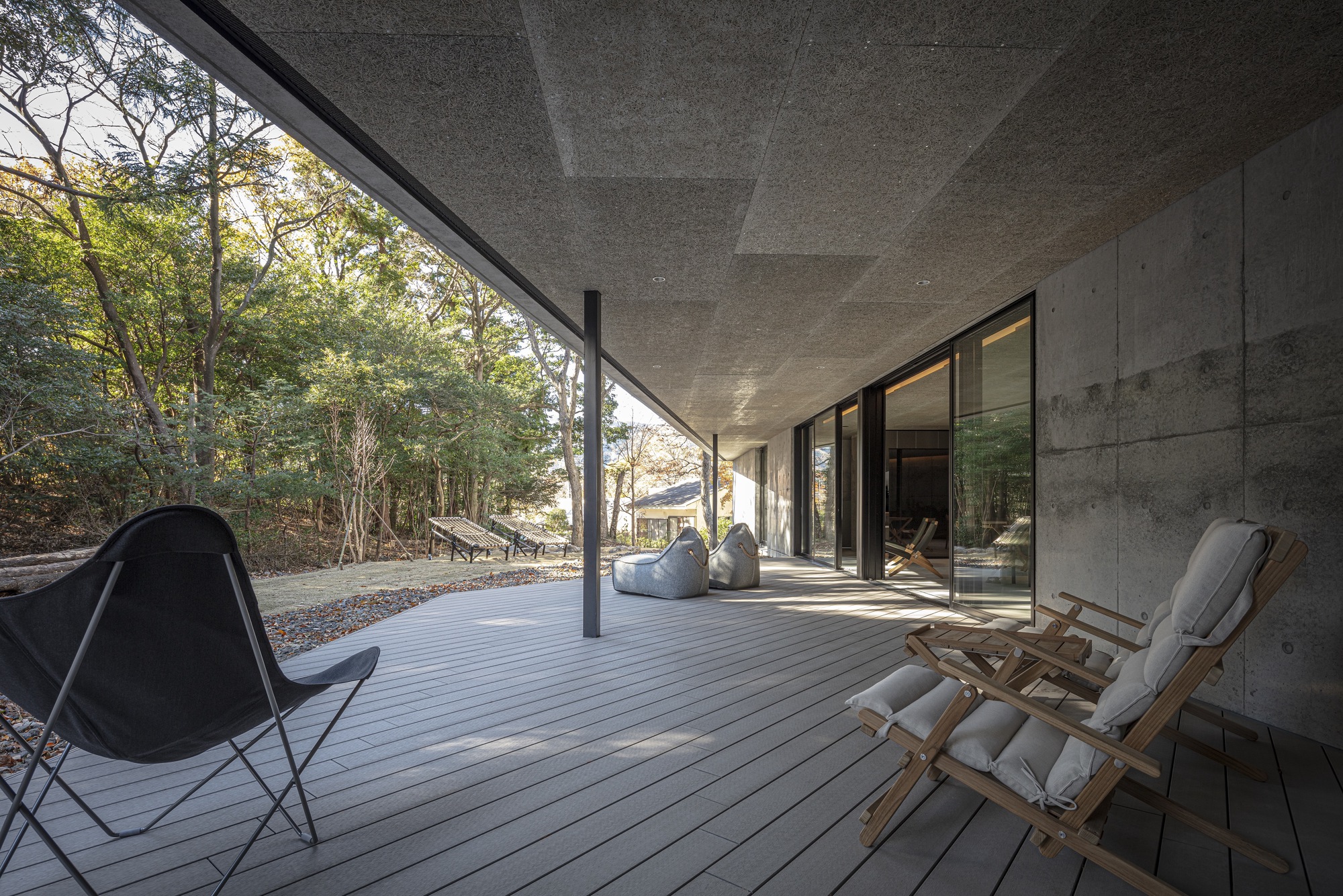 Covered timber deck terrace with folding canvas chairs overlooking wooded hillside in afternoon light