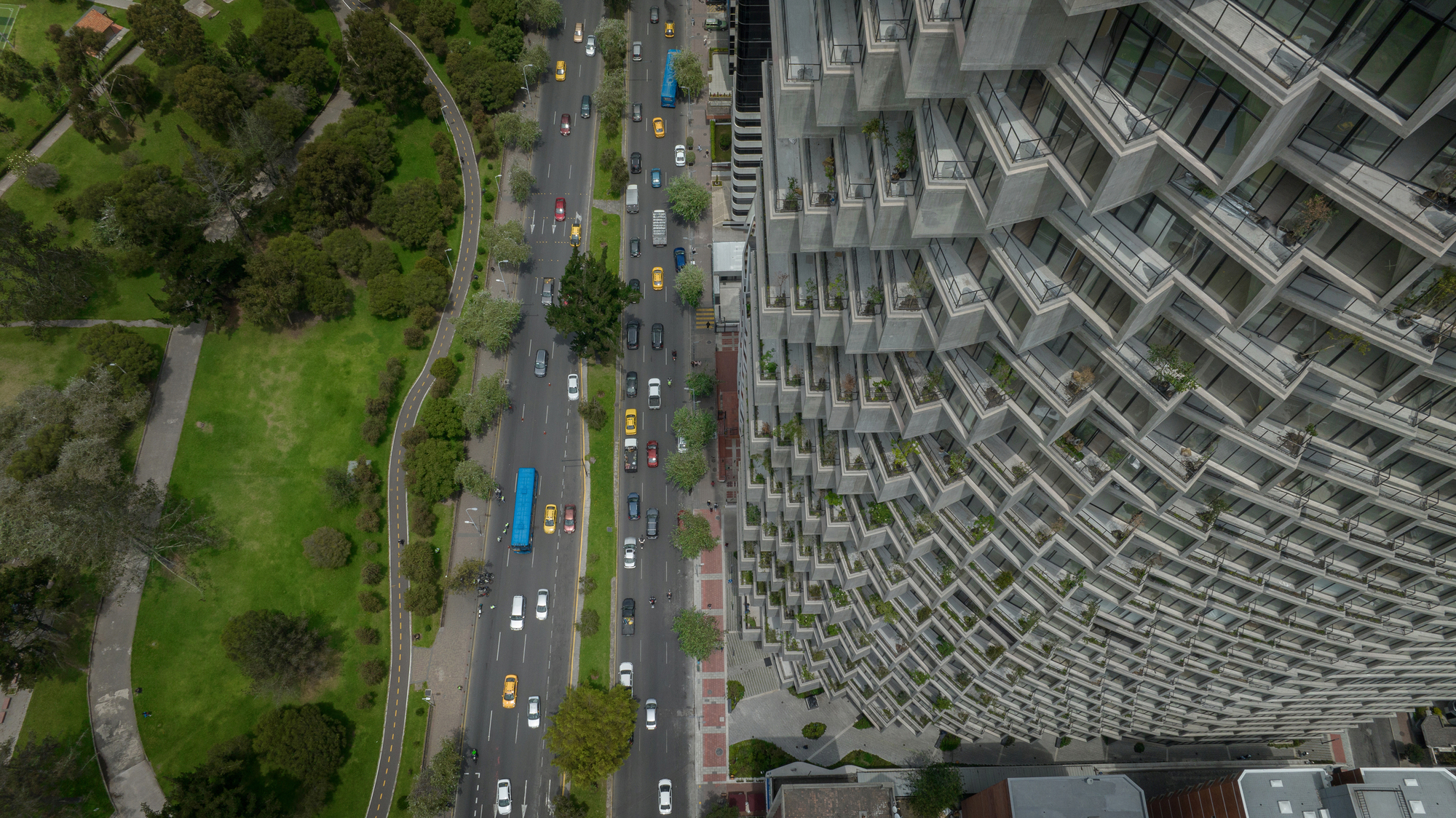 Aerial view of the terraced facade beside a tree-lined avenue with passing traffic