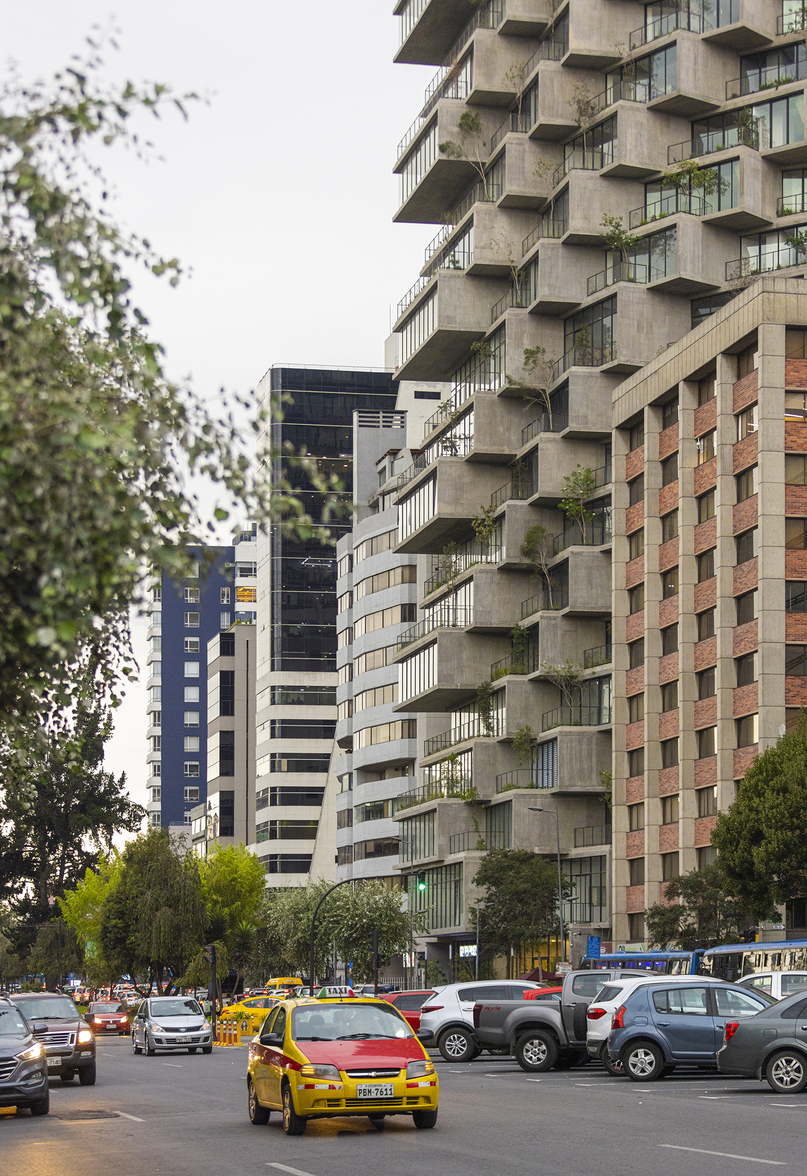 Street view of the stepped balcony facade with trees and yellow taxis in foreground