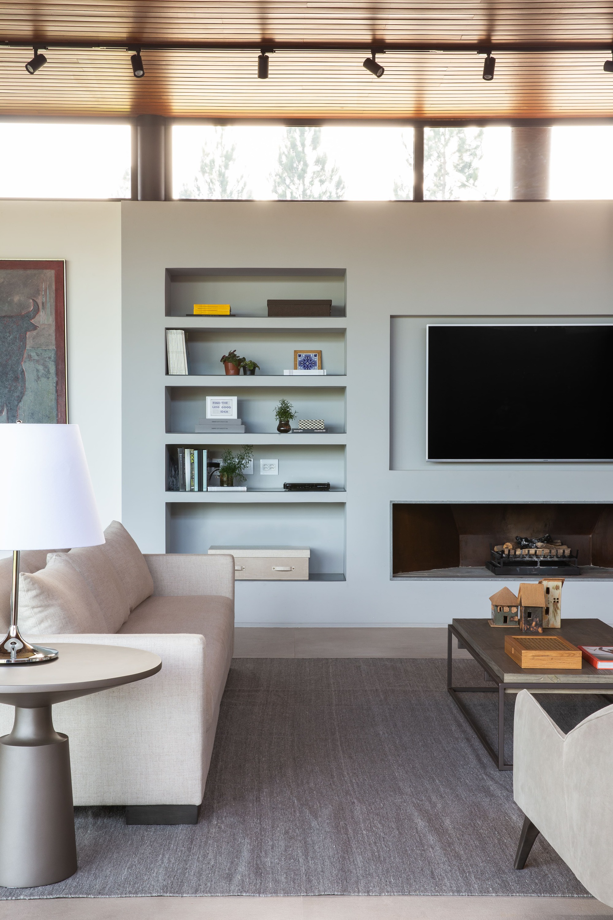 Living room with white built-in shelving and a horizontal fireplace below a mounted television
