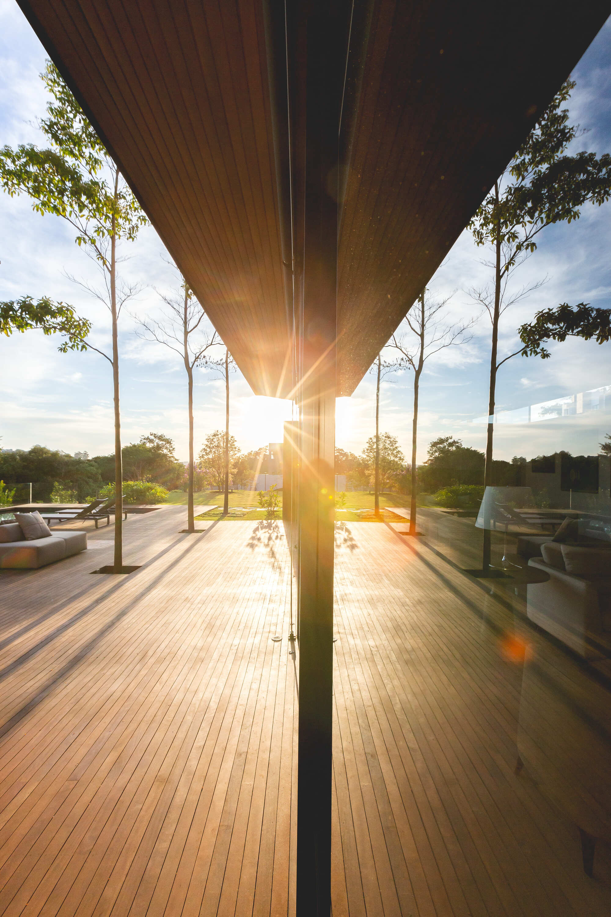 Underside view of the timber-clad overhang with sunburst filtering through the column at sunset