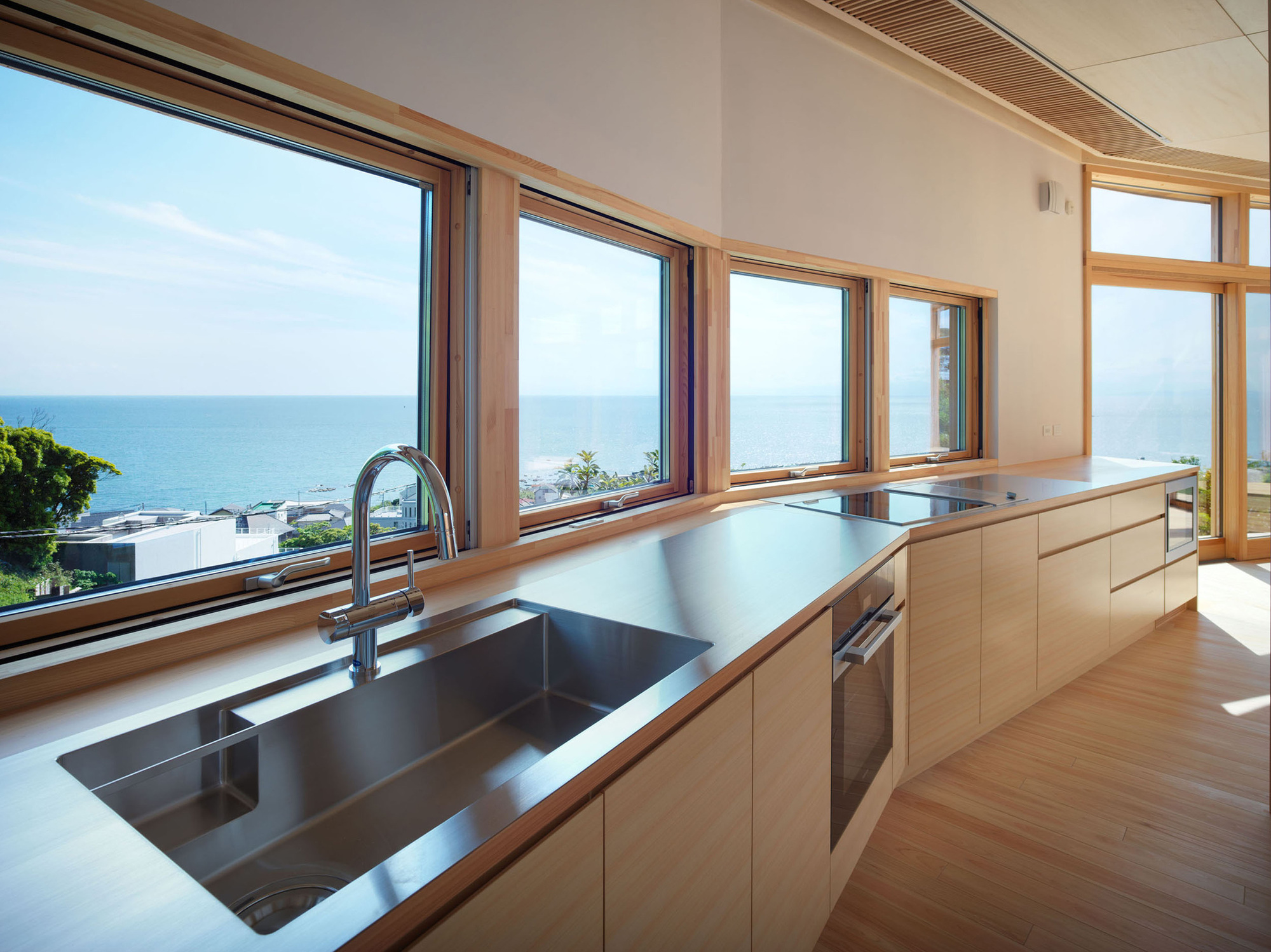 Kitchen with stainless steel countertop and timber-framed windows overlooking the ocean