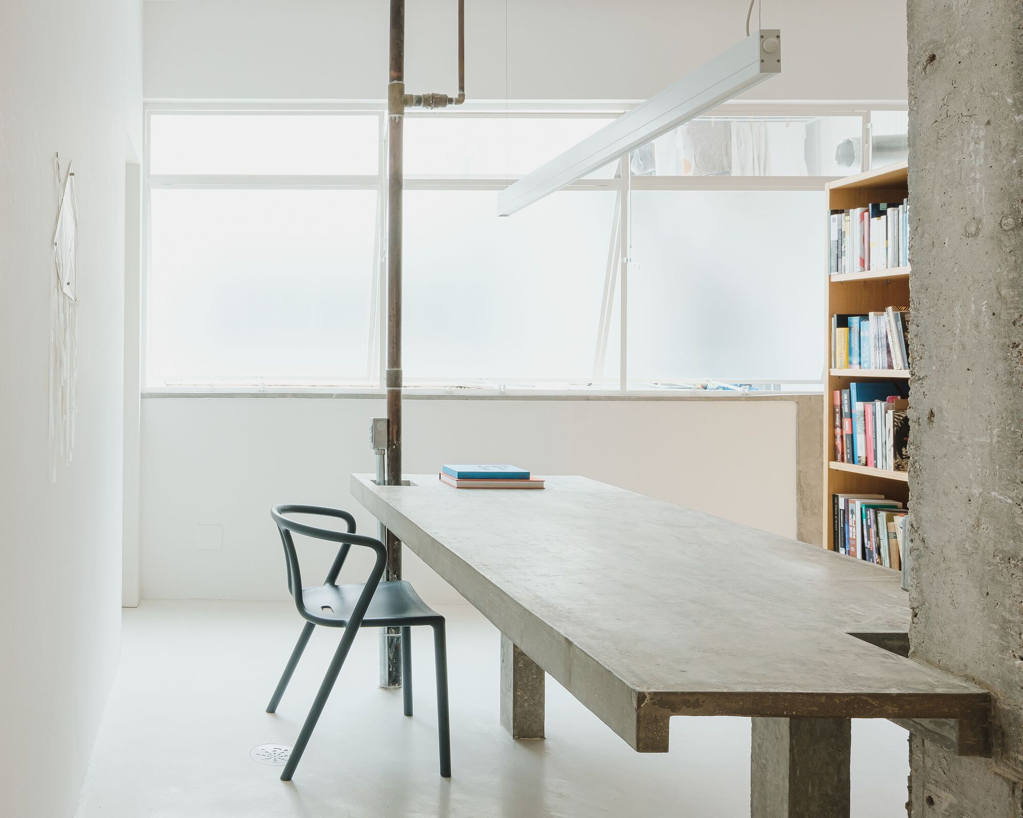 Work table at frosted glass window with steel pipe penetrating the concrete surface