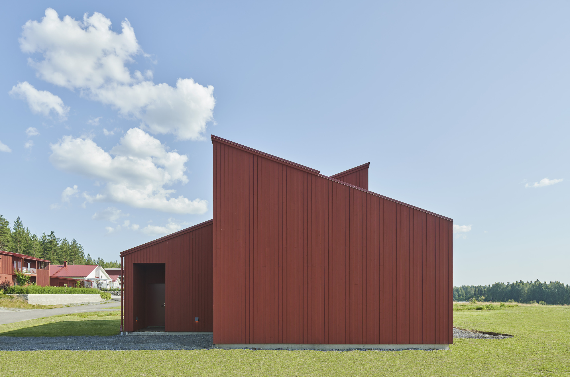End view of the red corrugated metal facade with stepped roofline against a summer sky