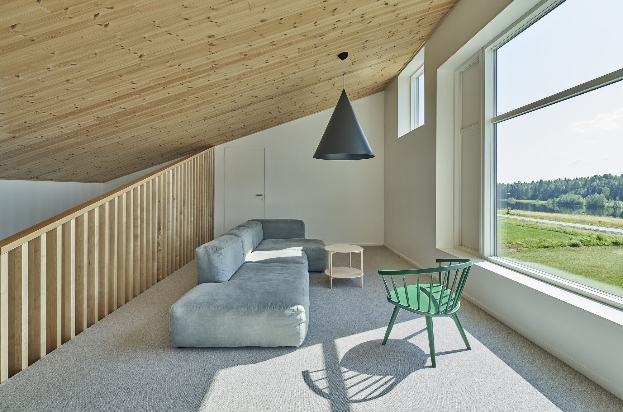 Upper level seating area with slatted wood railing and sloped timber ceiling under daylight