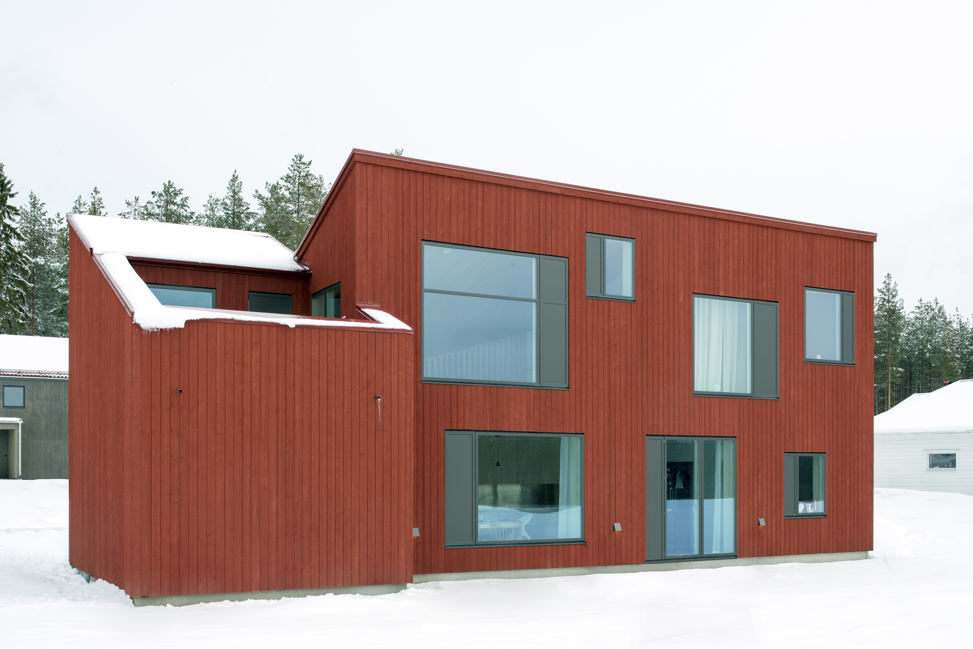 Garden facade of the red clad volumes with snow on the ground in winter