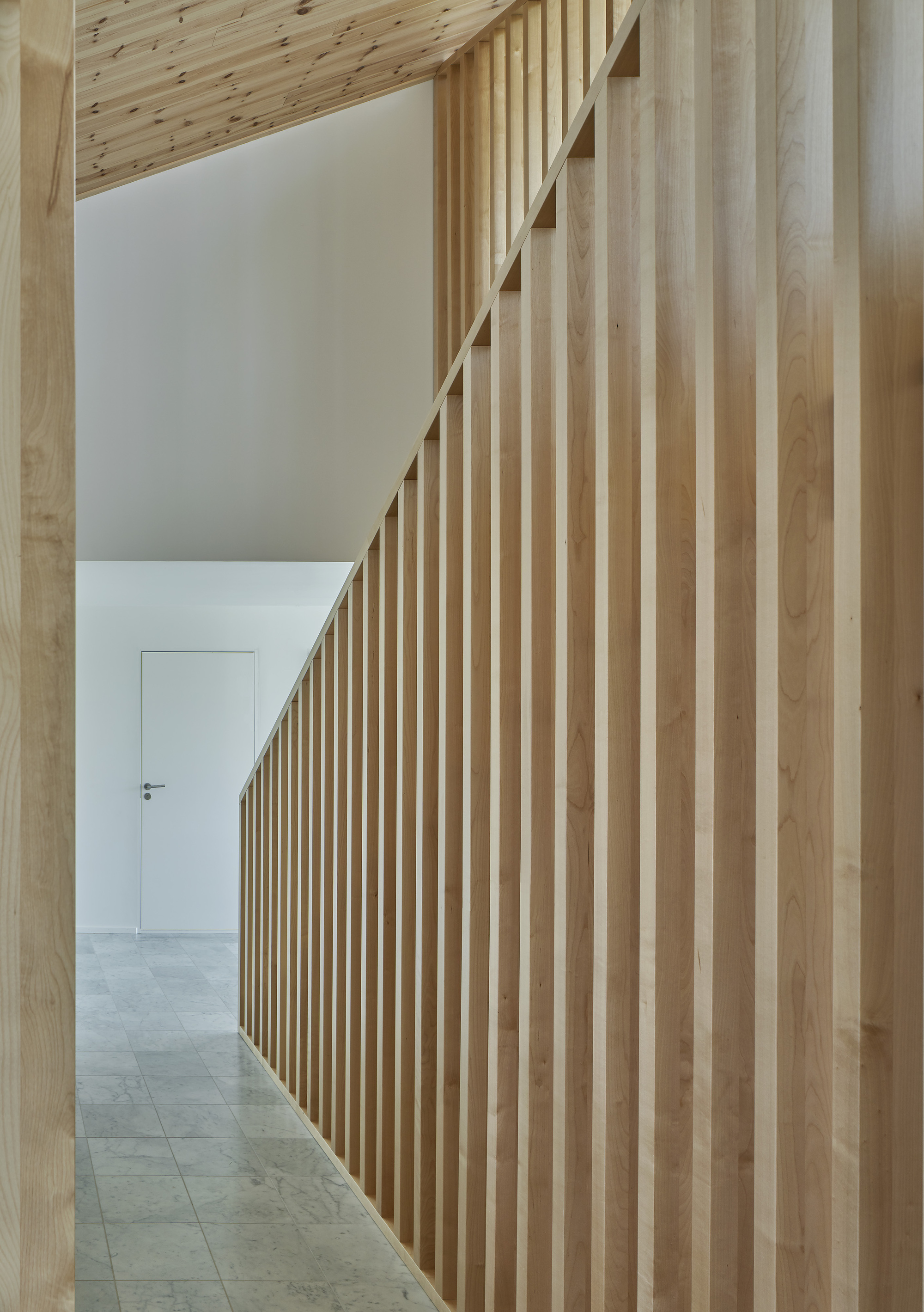 Hallway with vertical timber slat wall leading to a white door and exposed ceiling