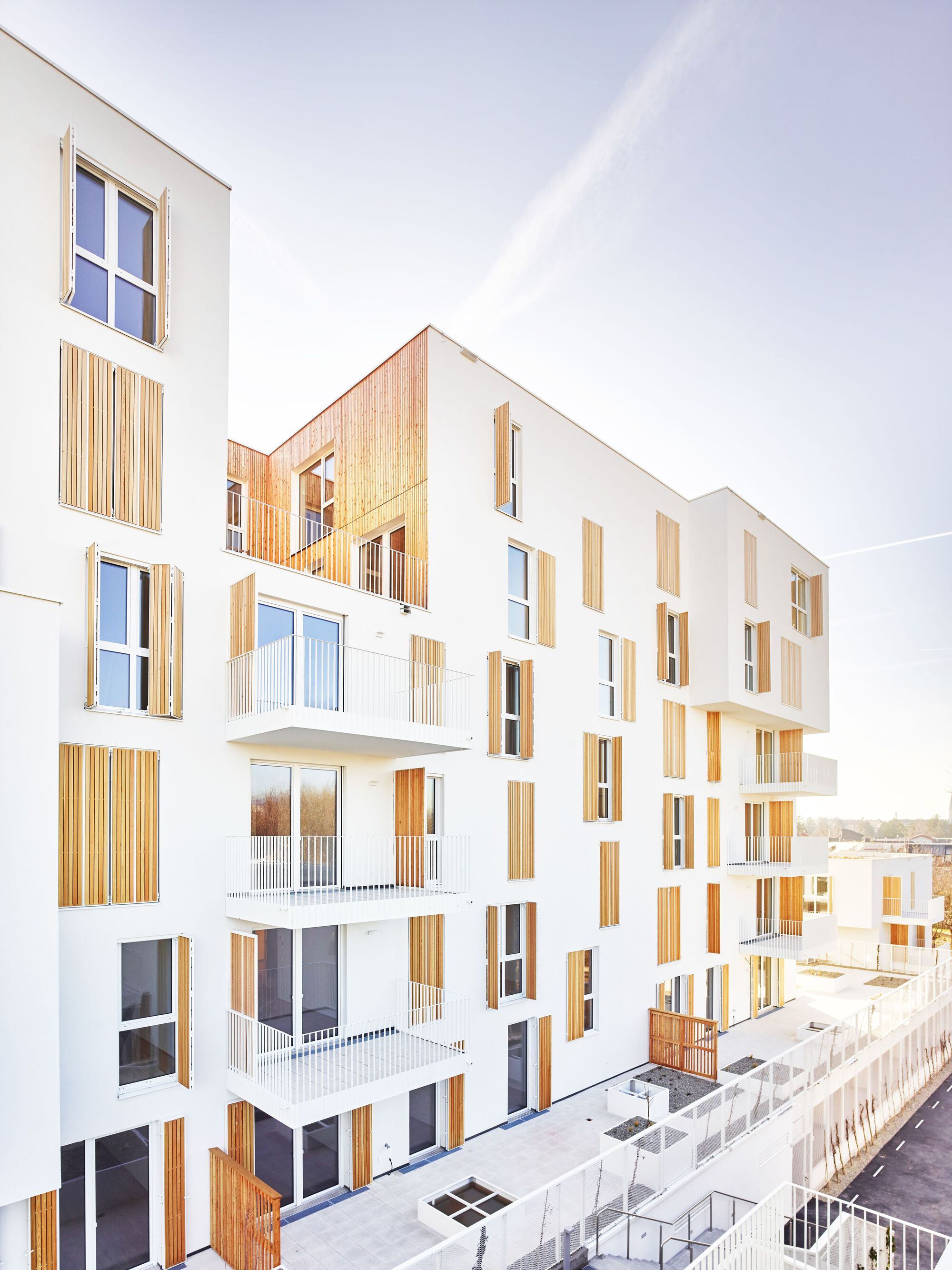 White facade with vertical timber shutters and projecting balconies under a rainbow