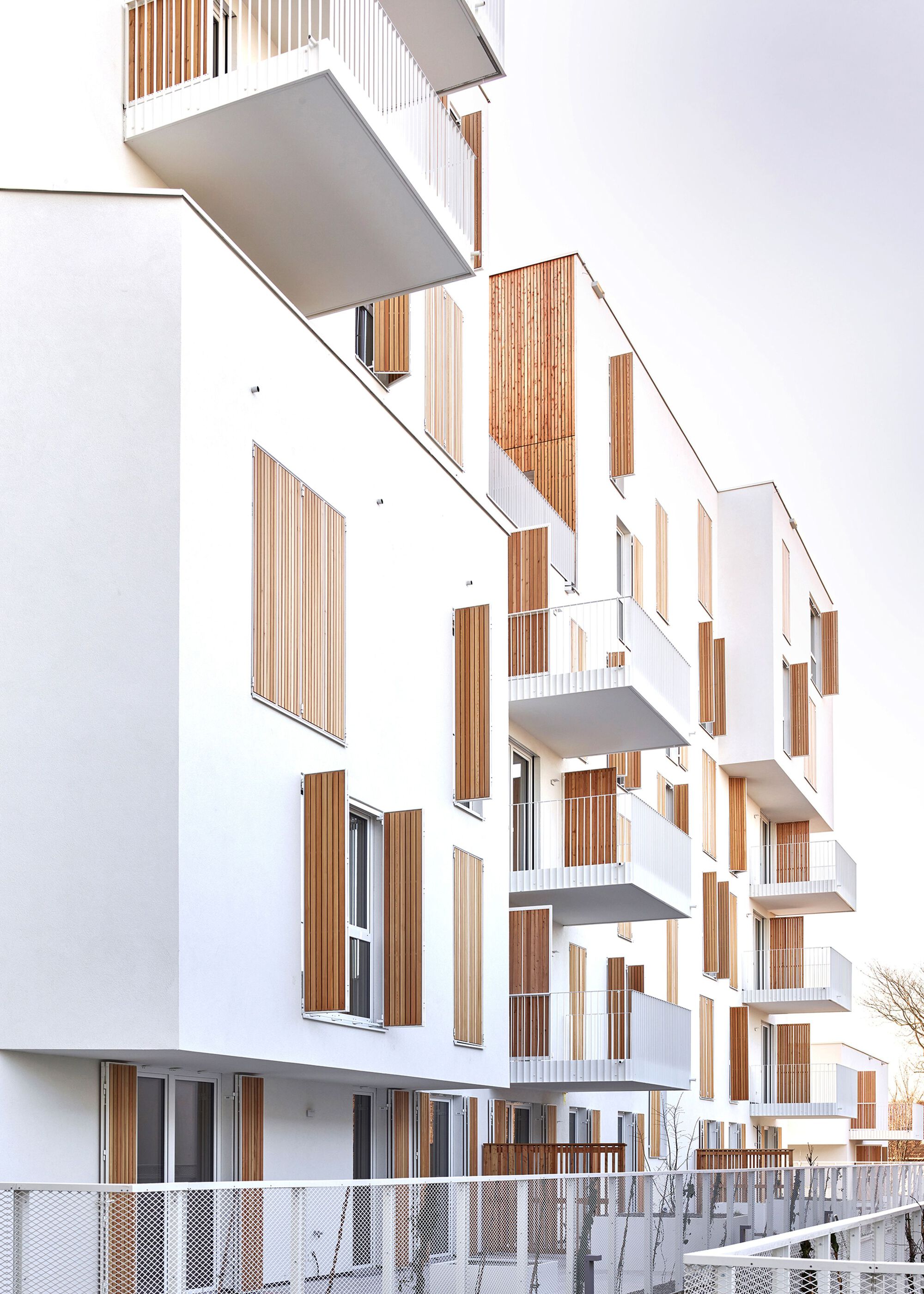 Oblique view of the staggered white balconies with vertical timber screening panels