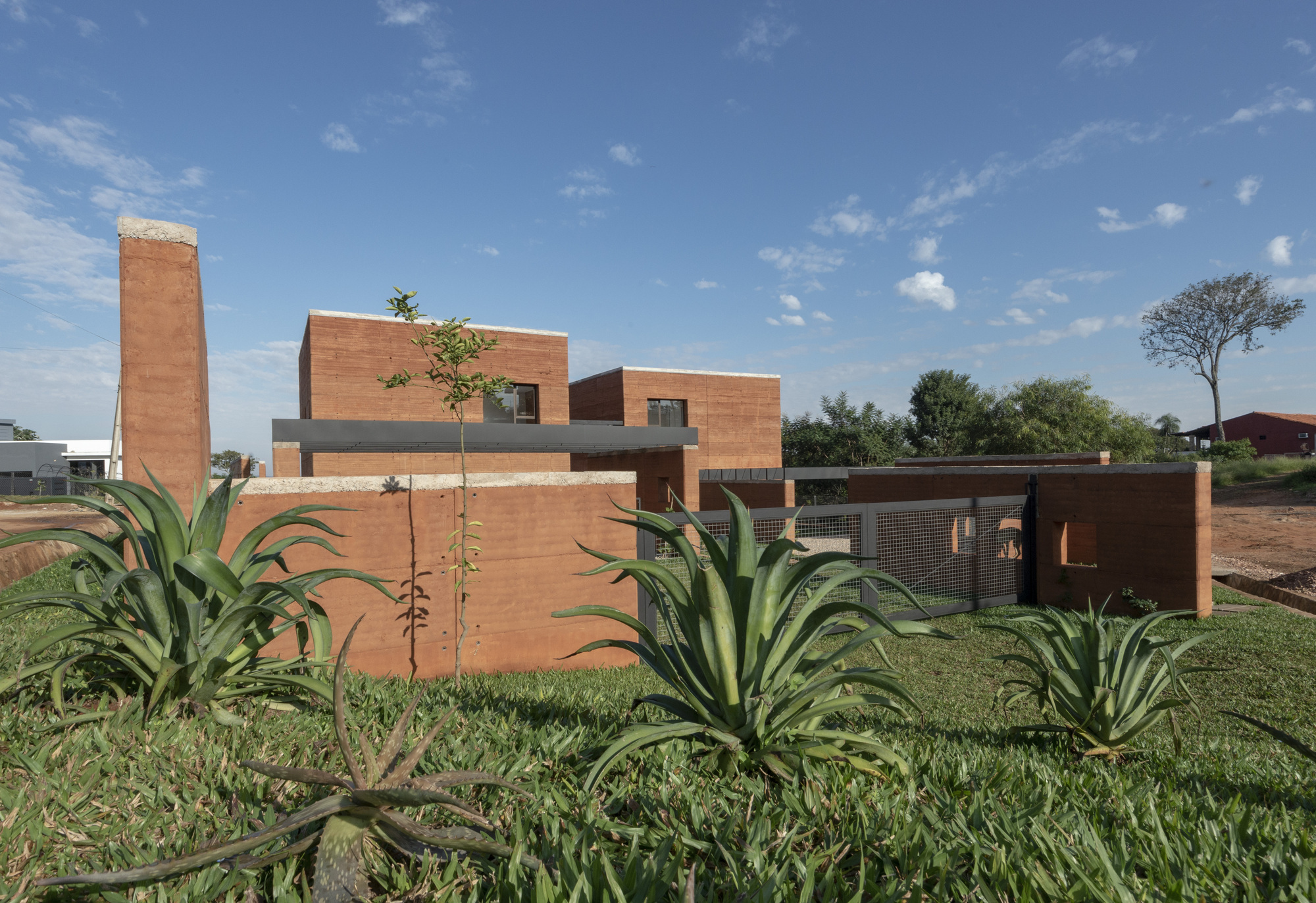 Side elevation showing rammed earth volumes and a planted bed of agave in the foreground