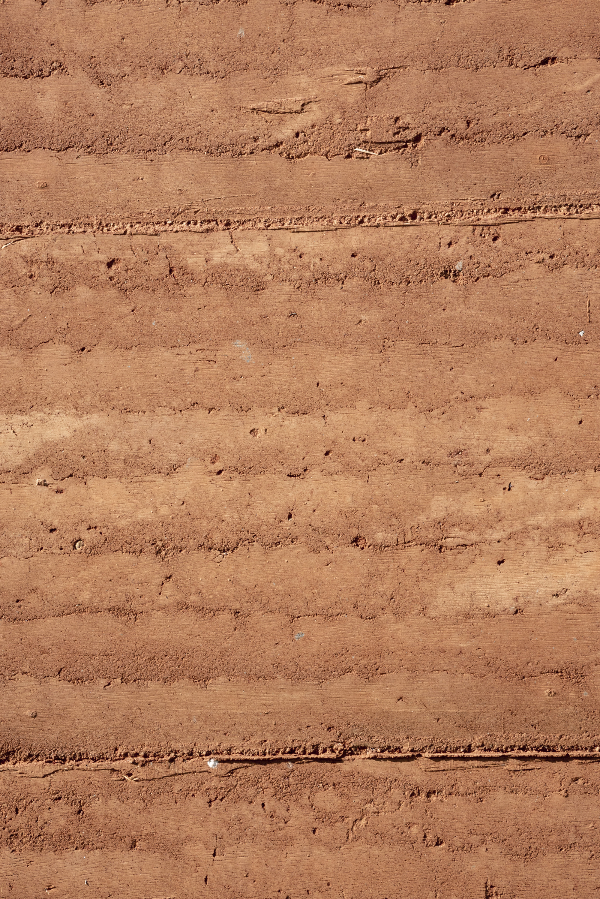 Close-up of layered rammed earth wall surface showing horizontal stratification and natural texture