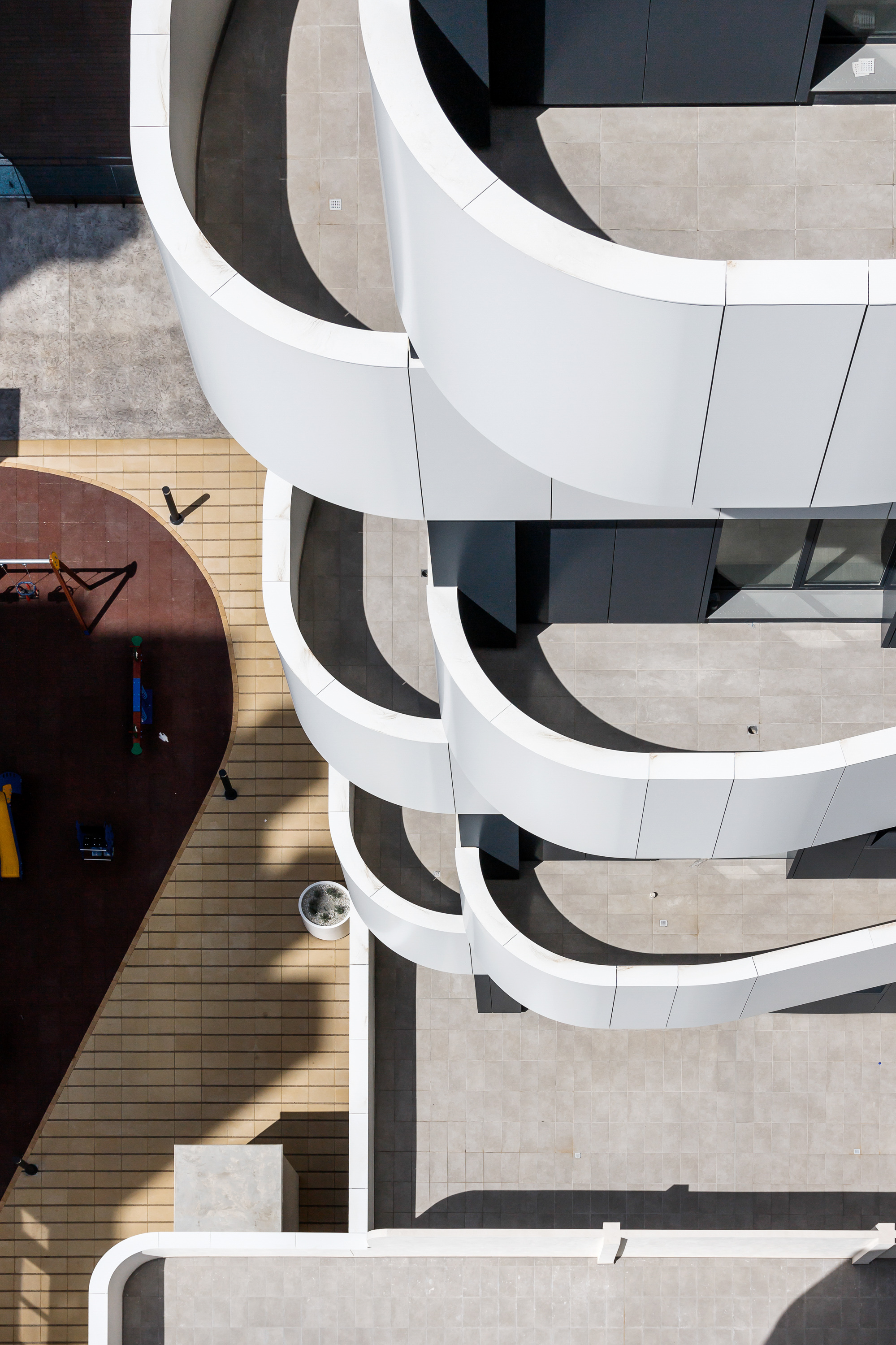 Aerial view of the curved balconies with people on the deck and shadows cast by afternoon sun