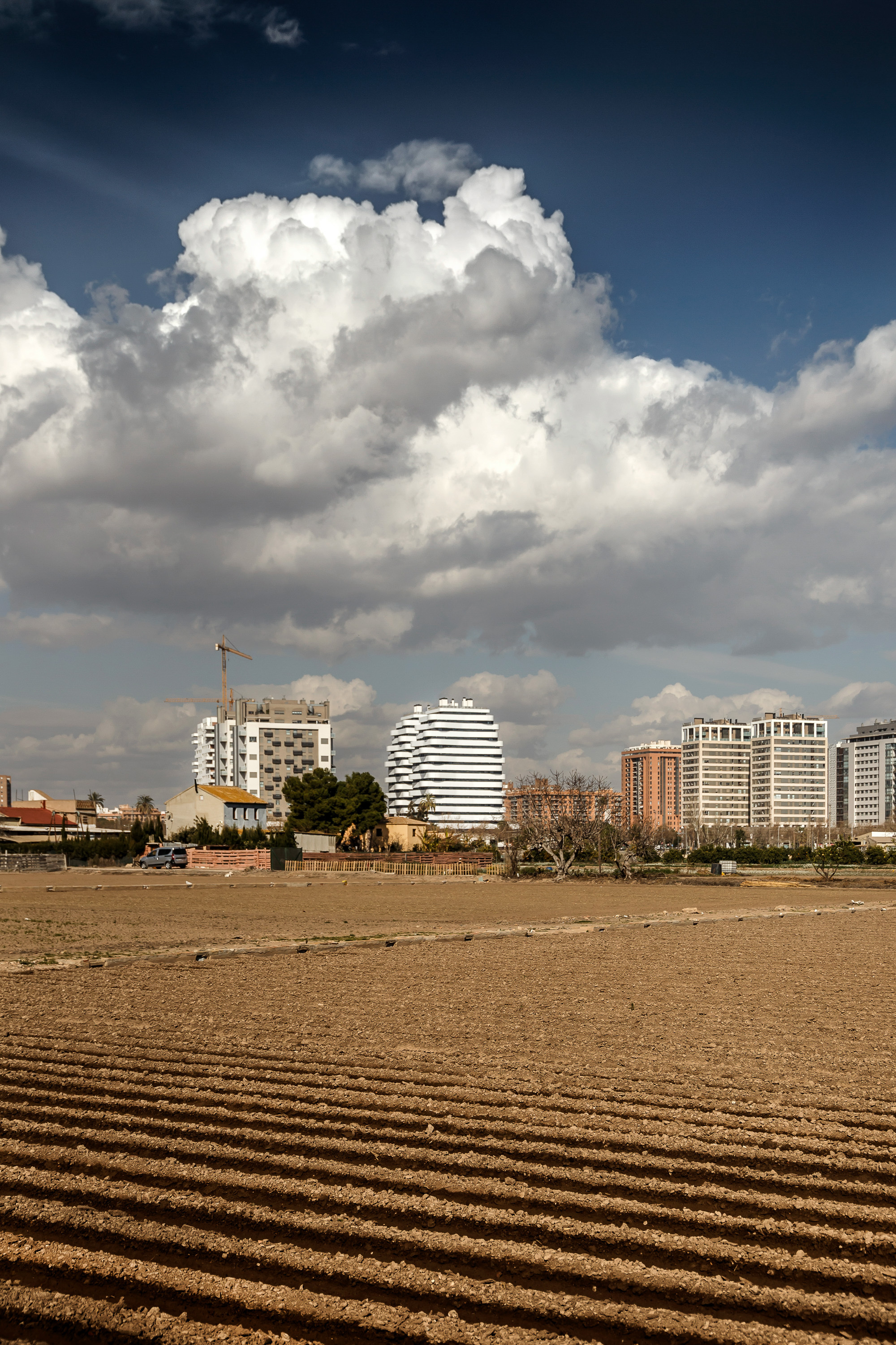 Distant view of the cylindrical tower with horizontal banding across a sandy beach under dramatic clouds