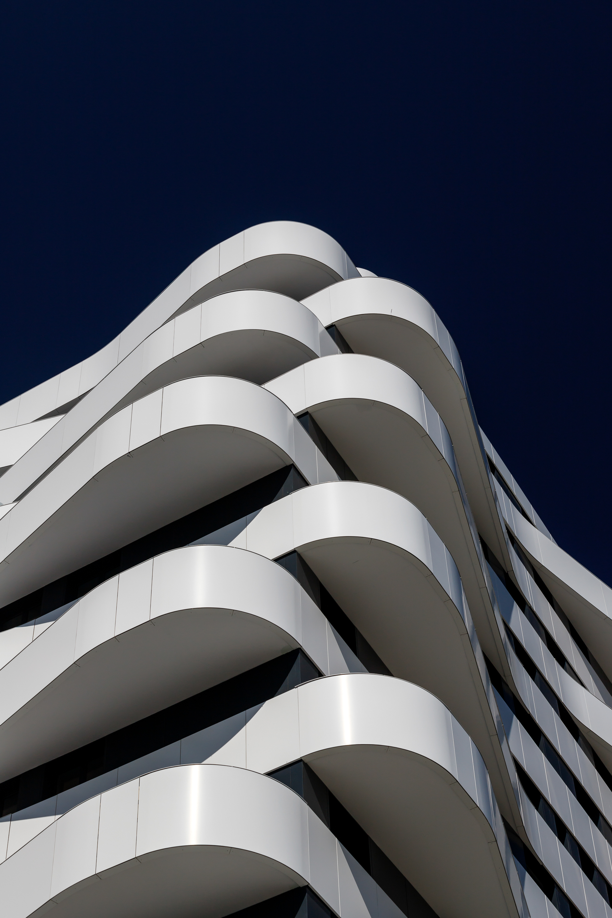 Corner detail of the spiraling white balcony edges against a dark evening sky