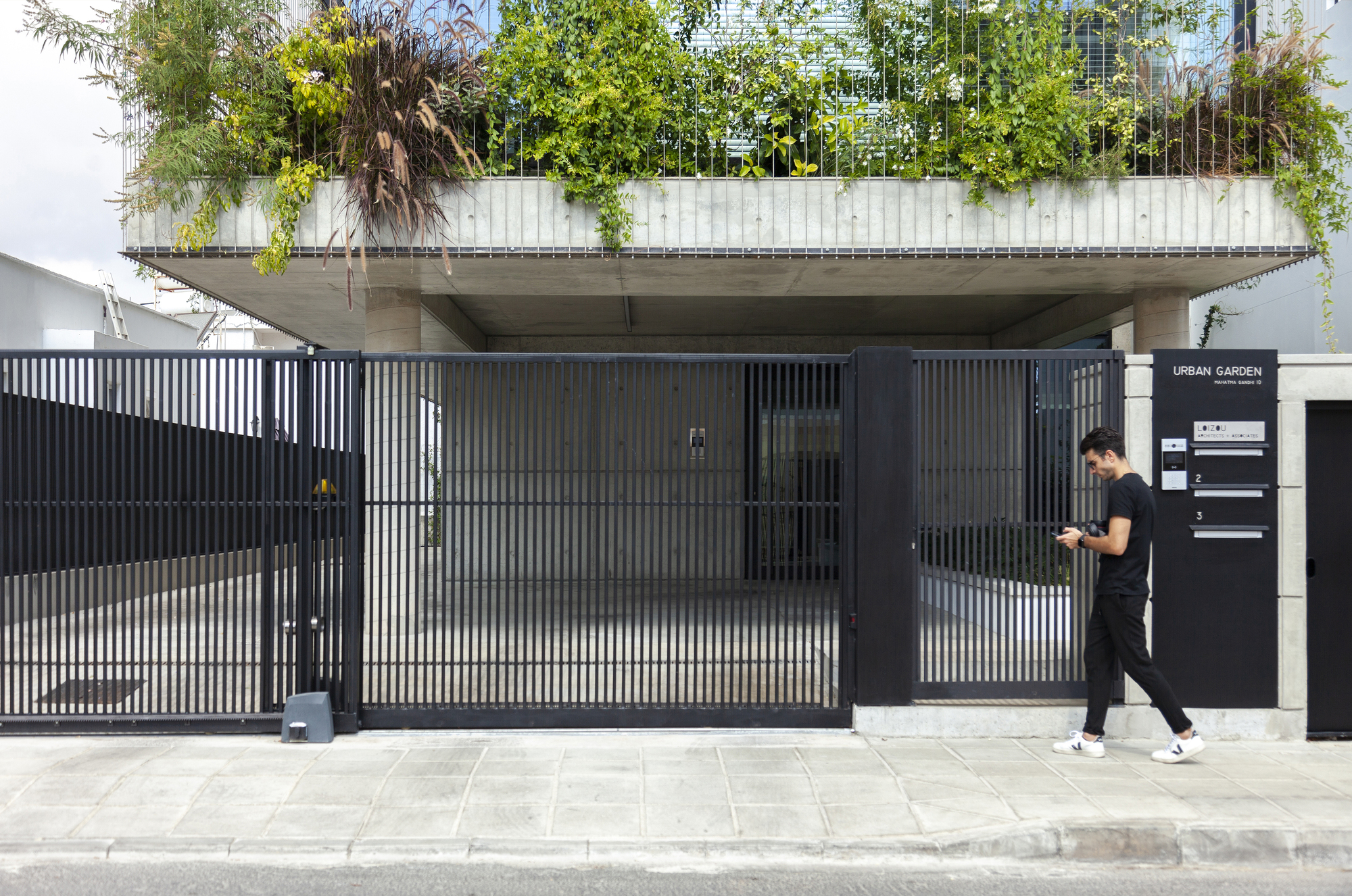 Ground-level entrance with corrugated metal gate and a person walking past on the sidewalk