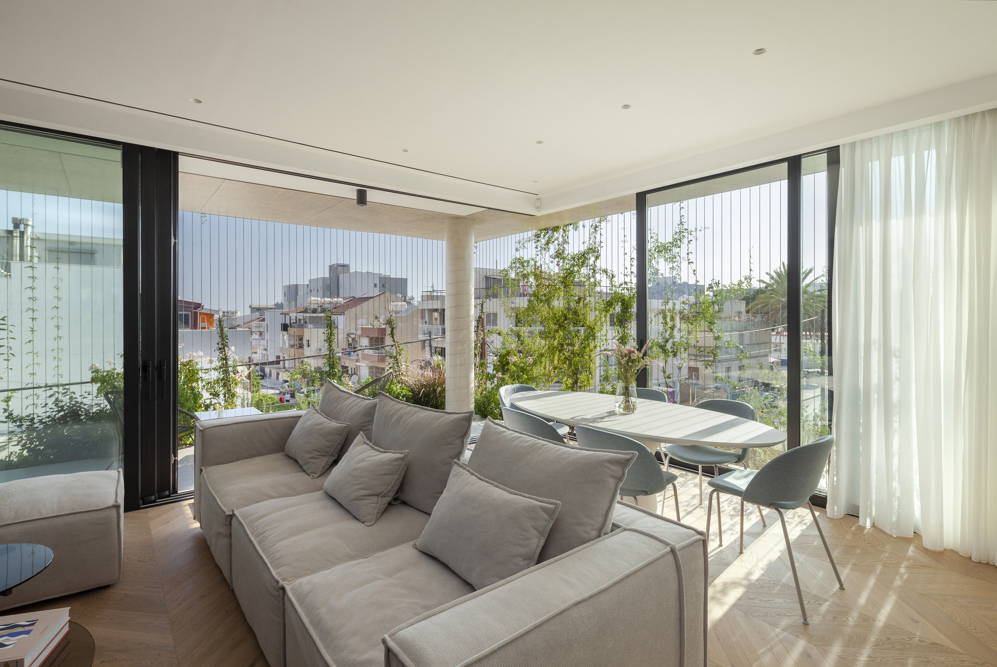 Living room opening onto terrace with vertical green screen and views across the low-rise neighborhood