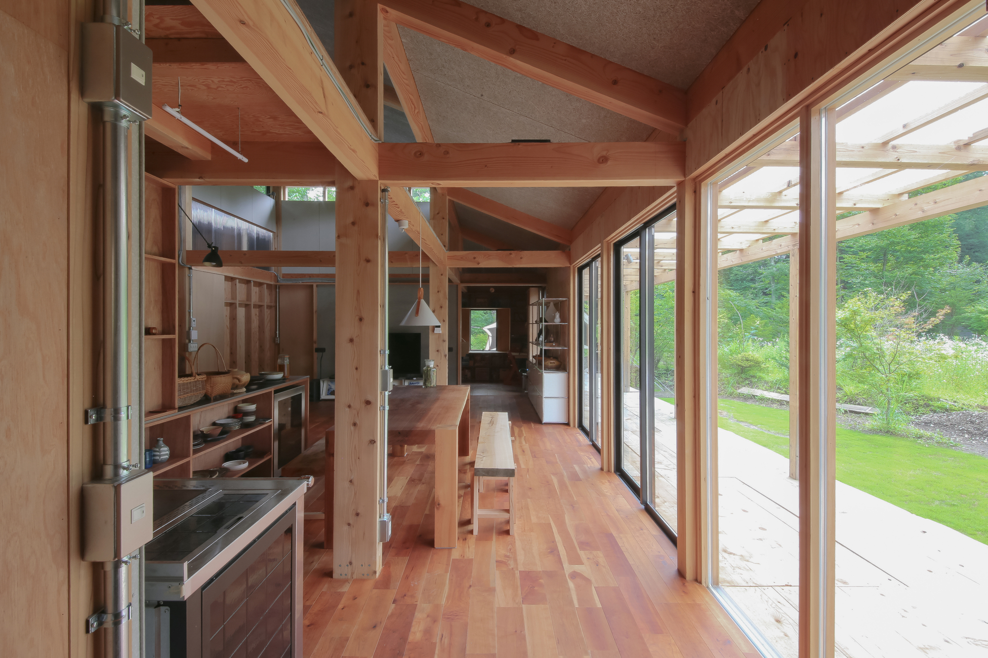 Living and dining space with exposed post-and-beam structure and full-height glass doors opening to garden