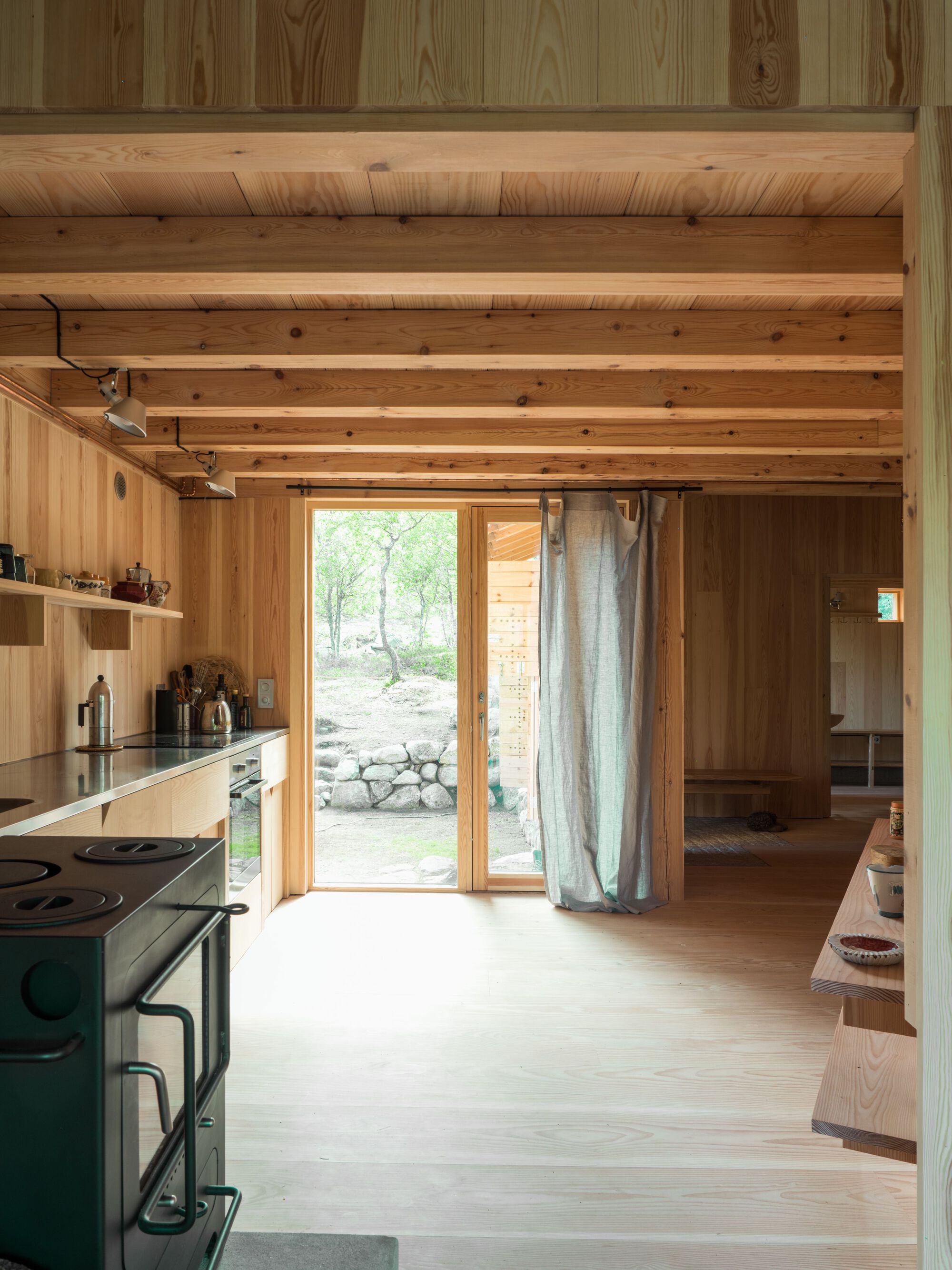 Kitchen with exposed ceiling beams and glazed door framing a view to the stone landscape outside