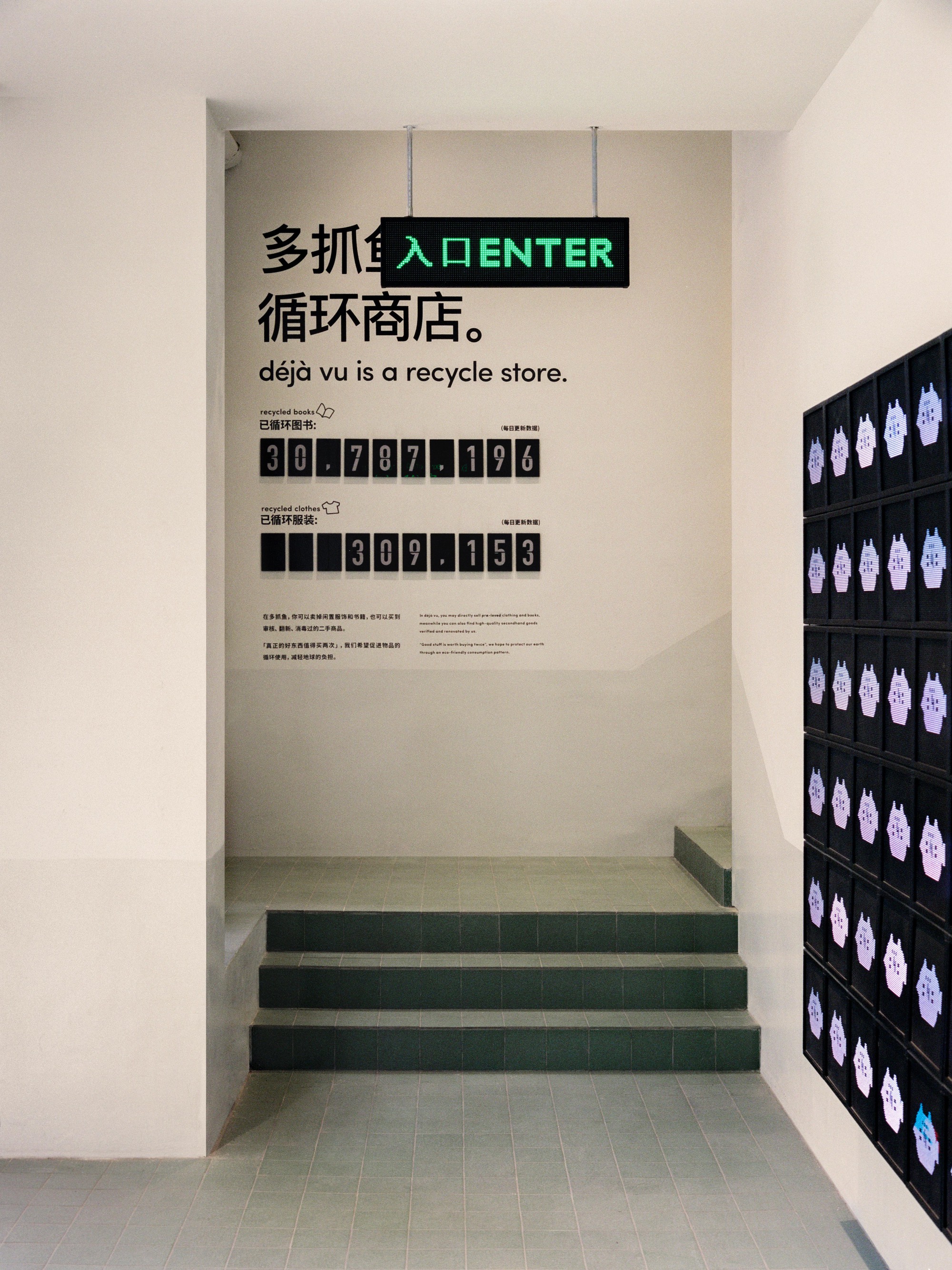 Entry vestibule with dark green tiled steps and bilingual wall graphics beside a backlit display