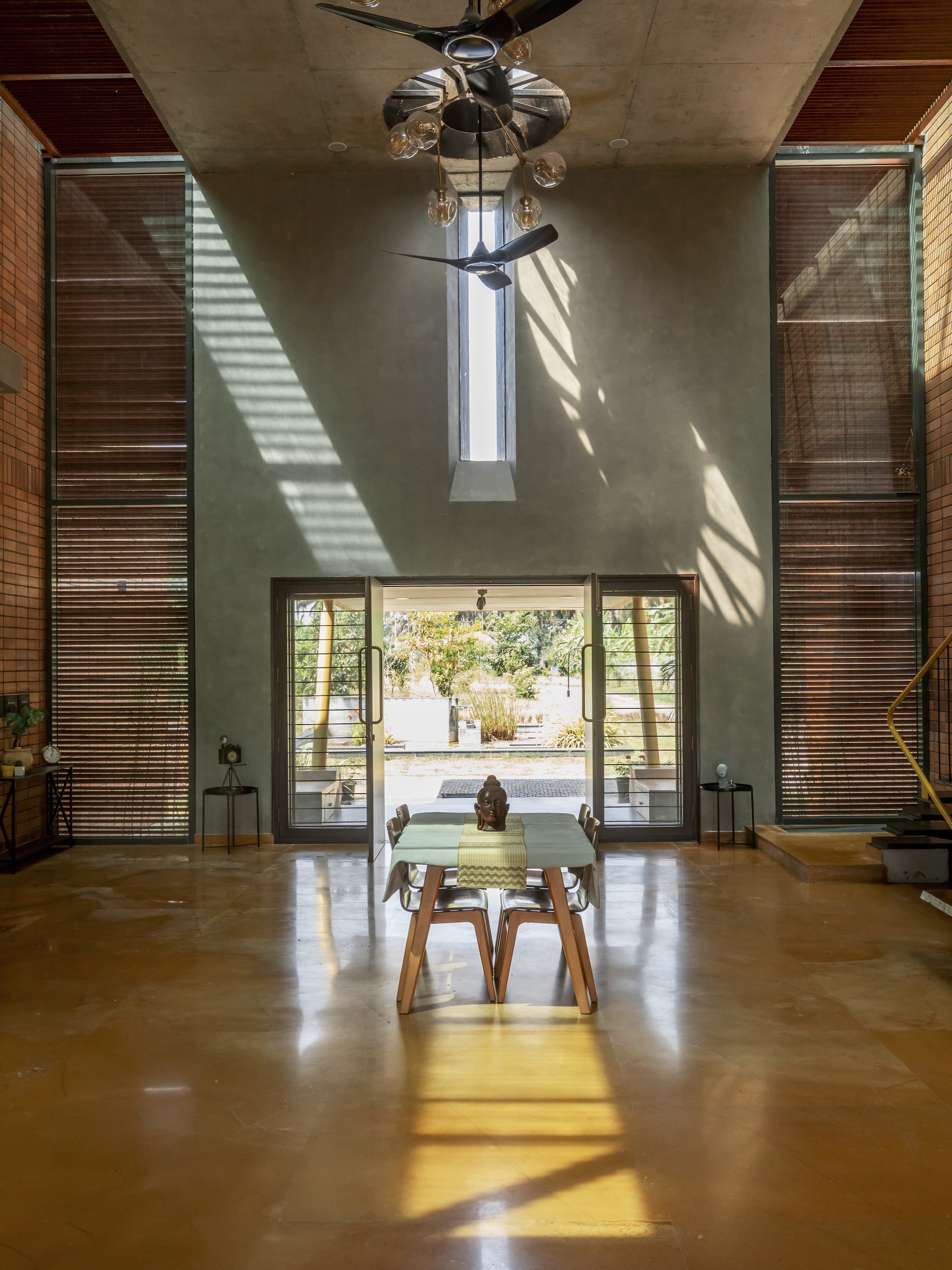 Double-height living space with slatted timber screens and skylight casting diagonal shadows
